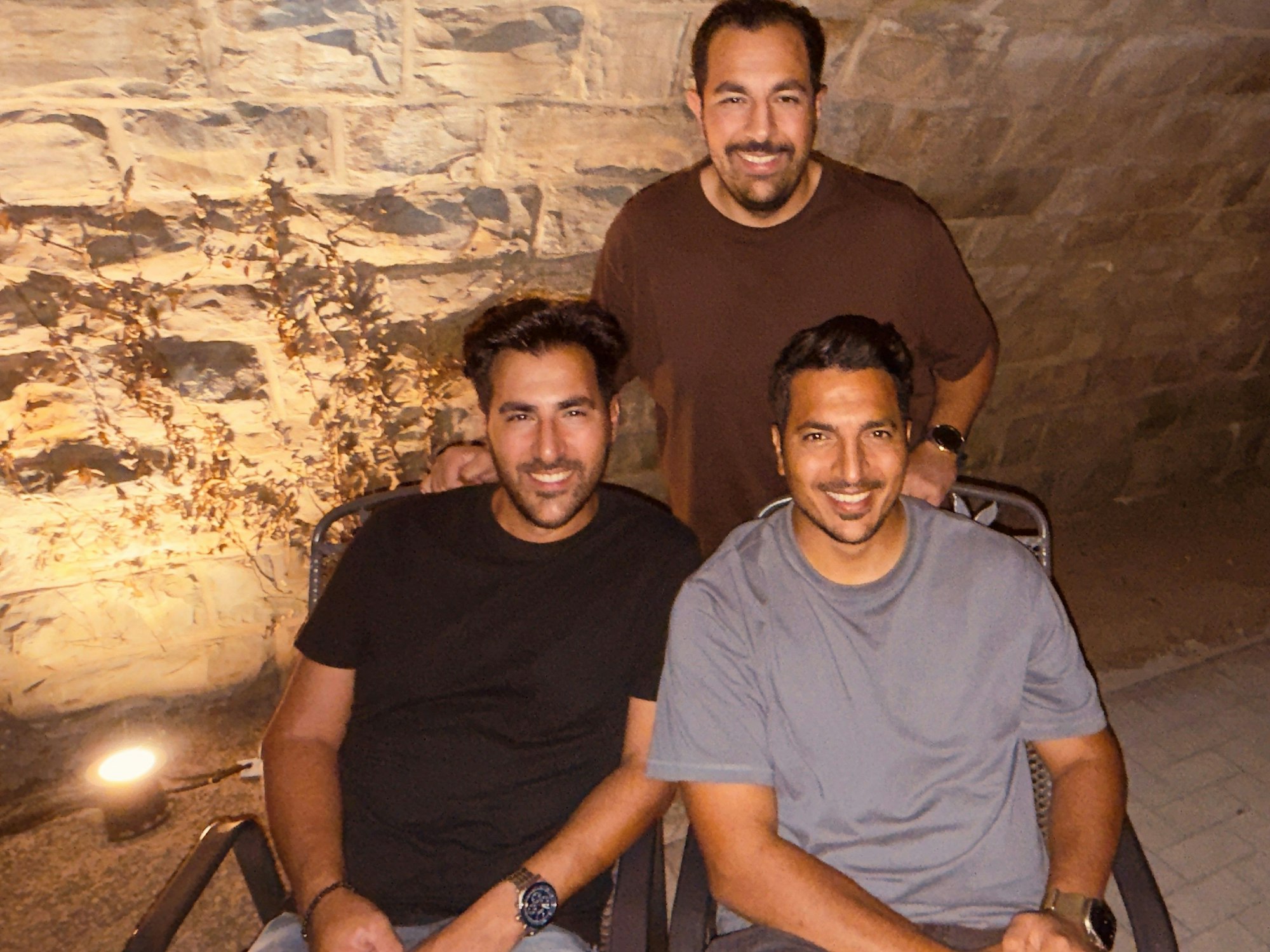 Drei Brüder sitzen vor einer beleuchteten Brücke.