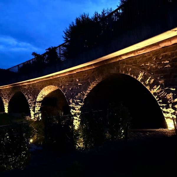 Eine angeleuchtete Bogenbrücke.