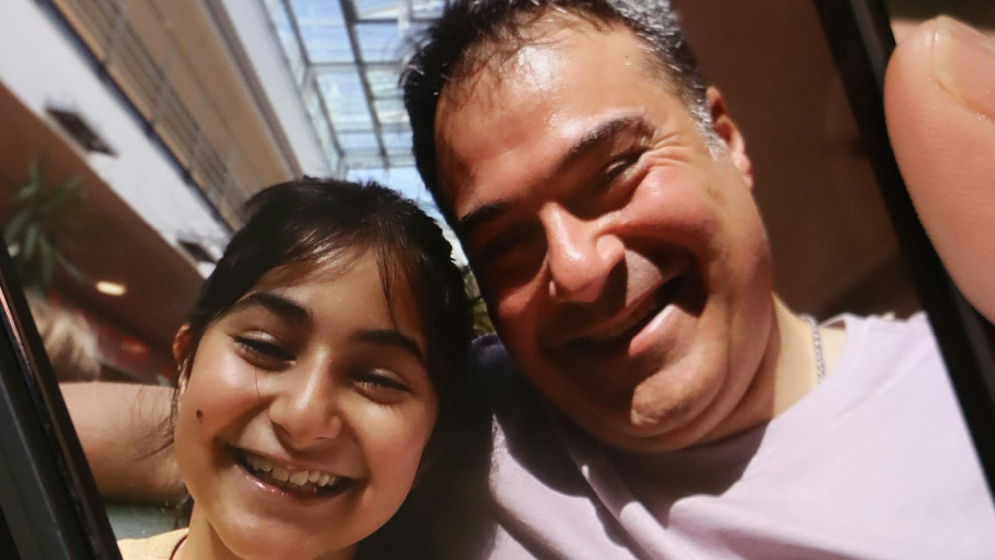 Auf dem Bildschirm eines Smartphones ist ein Foto von einem Mann und seiner Tochter zu sehen.