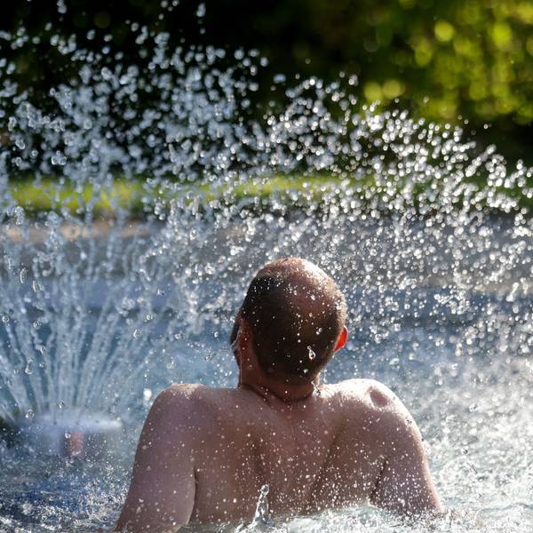 Das Bild zeigt einen Mann, der sich im Freibad an einem Wasserspiel erfrischt. Foto: Thomas Warnack/dpa