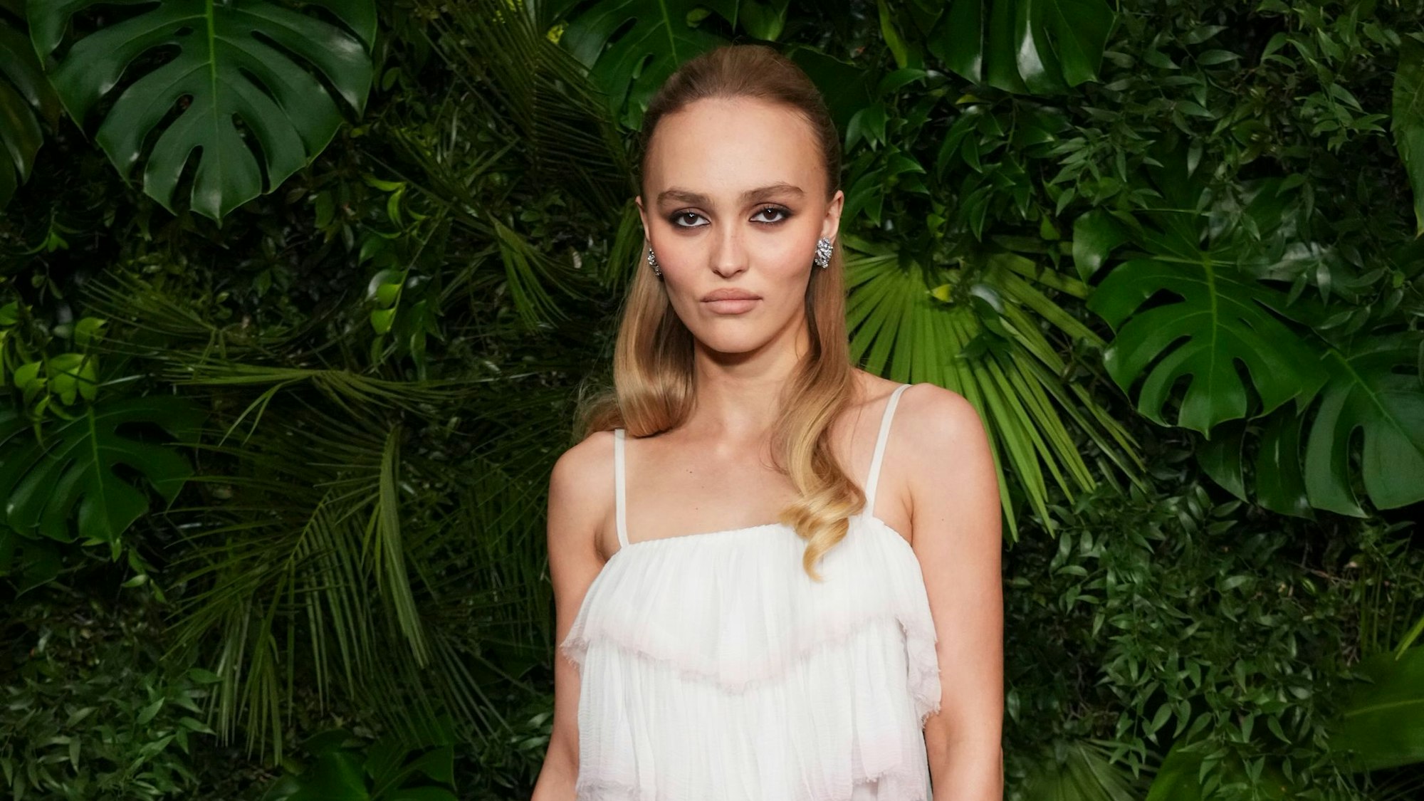 Schauspielerin Lily-Rose Depp schaut in typischer roter Teppich-Pose mit kühler Miene in die Kamera. (Archivbild)
