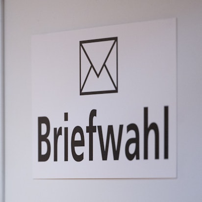 Das Wort Briefwahl ist im Foyer des Rathauses an einer Wand zu sehen.