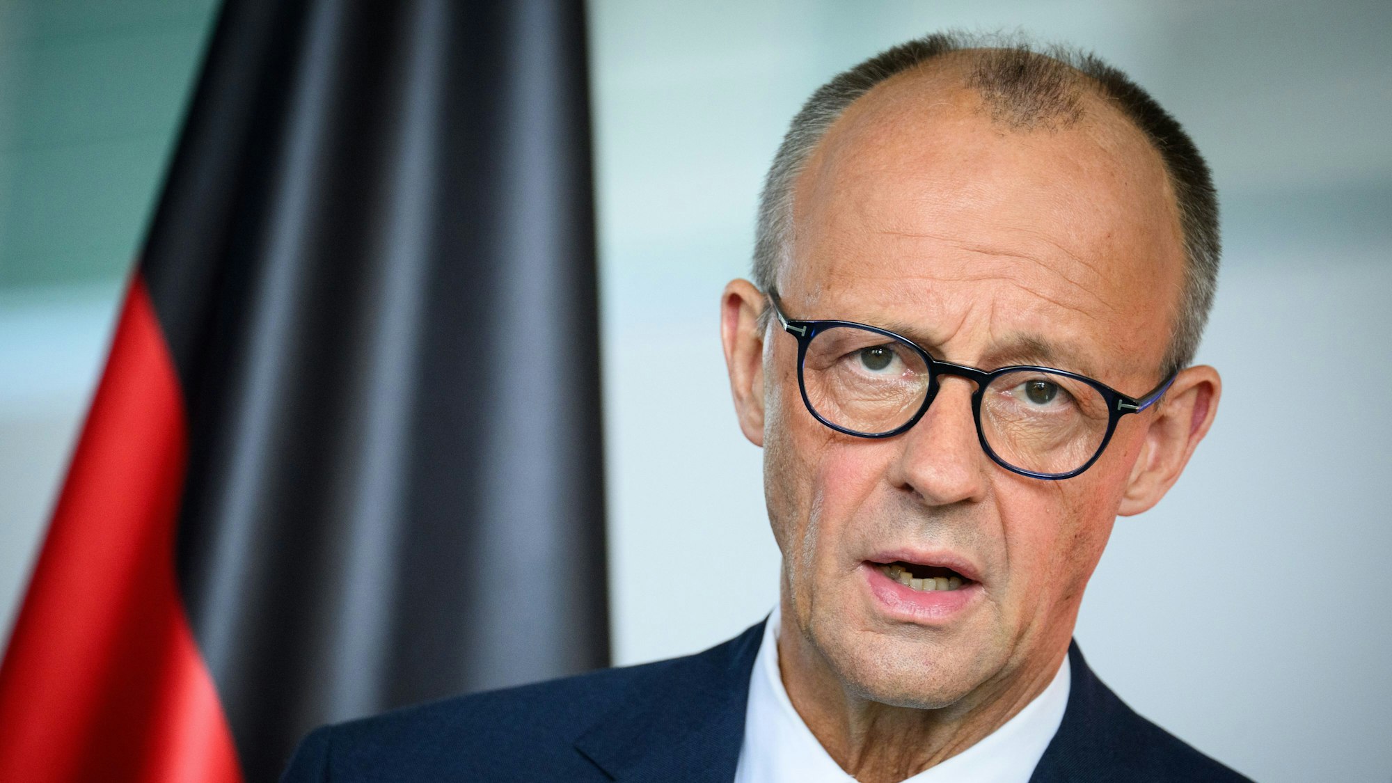 Merz vor einer Deutschlandflagge.