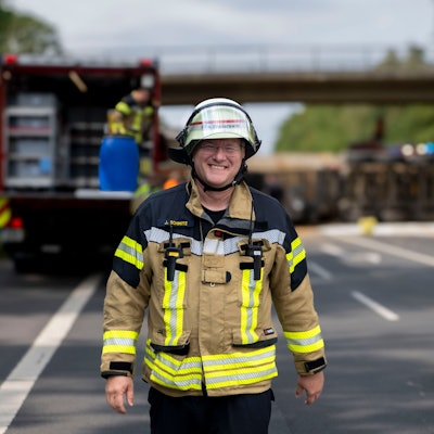 Das Bild zeigt Jürgen Schmitz in Feuerwehrmontur auf einer Straße.