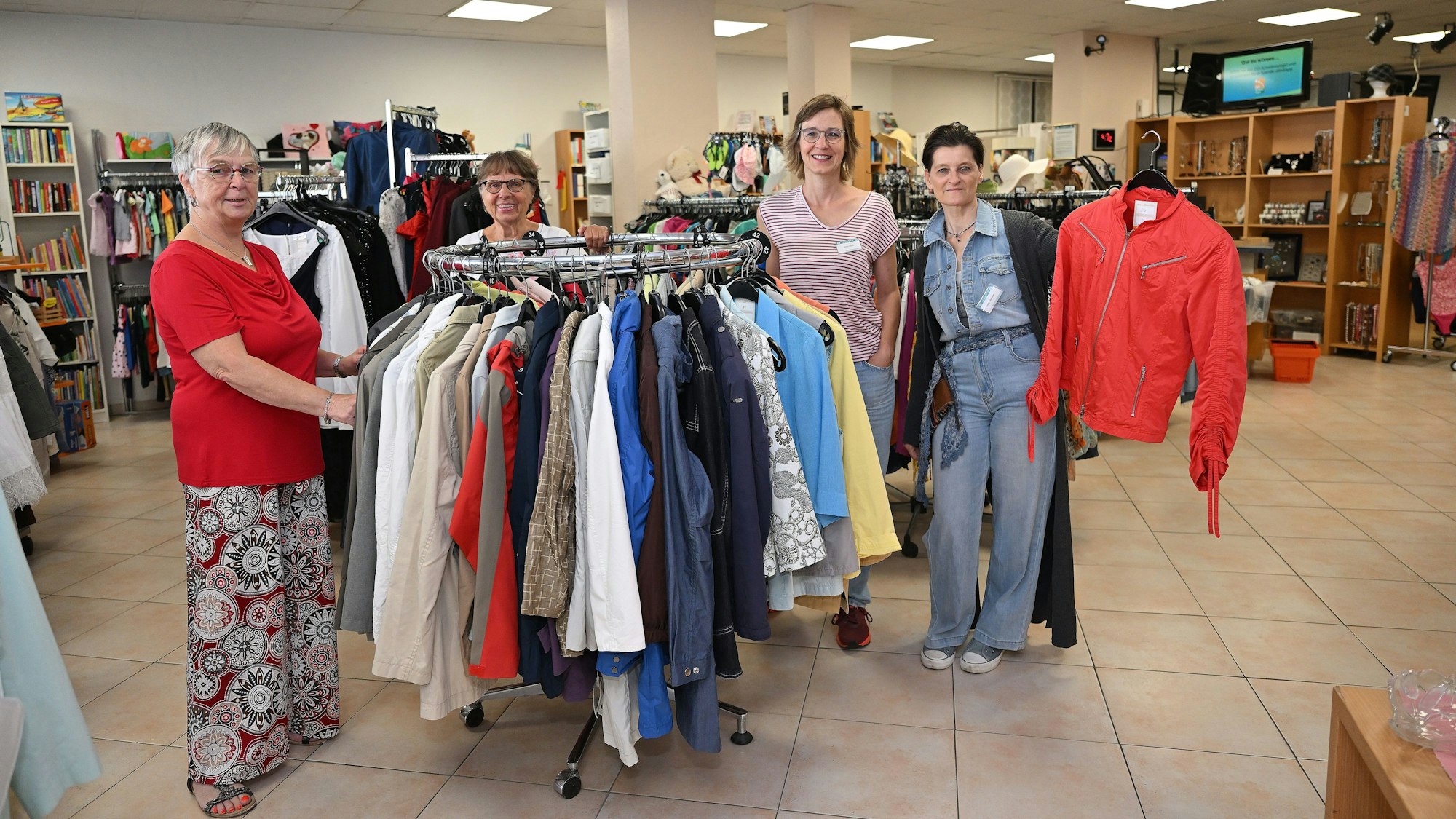 Vier Mitglieder des Adrashop-Teams stehen rund um eine Kleiderstange.