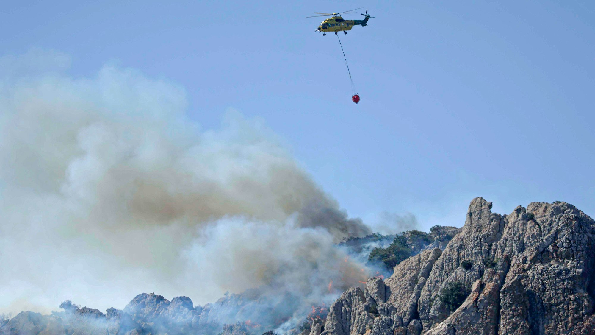 Ein Löschhubschrauber ist während eines Waldbrandes im spanischen Cadiz im Einsatz.