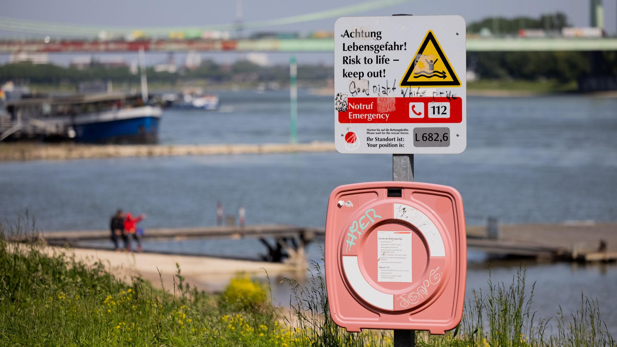 Ein Hinweisschild mit der Aufschrift „Achtung Lebensgefahr“ weist am Rhein in Köln-Rodenkirchen auf die Gefahren beim Schwimmen in dem Fluss hin.