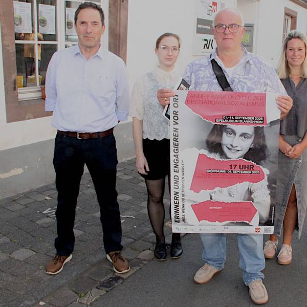 Drei Frauen und drei Männer, von denen einer ein Plakat hält, stehen vor dem Museum.