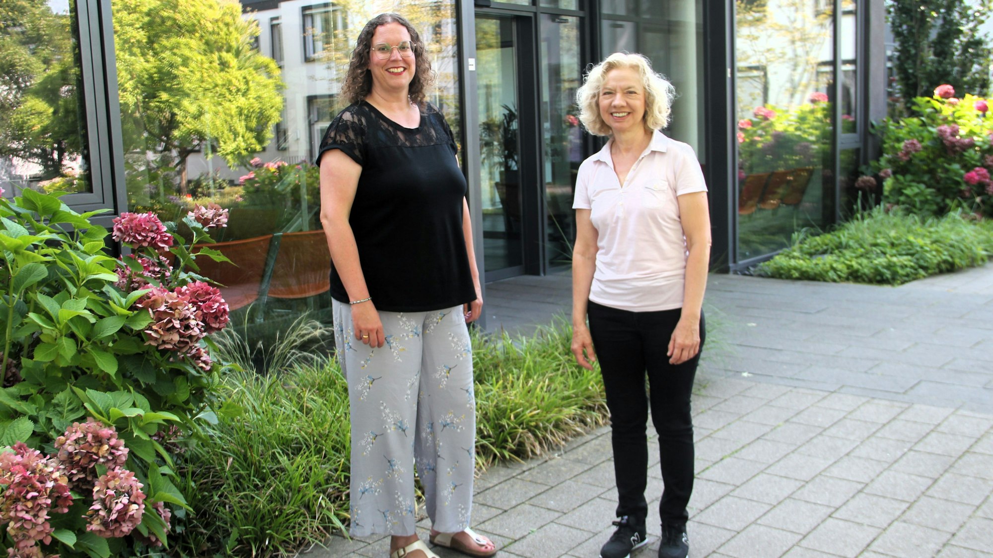 Zwei Frauen stehen vor einem Glas-Eingang