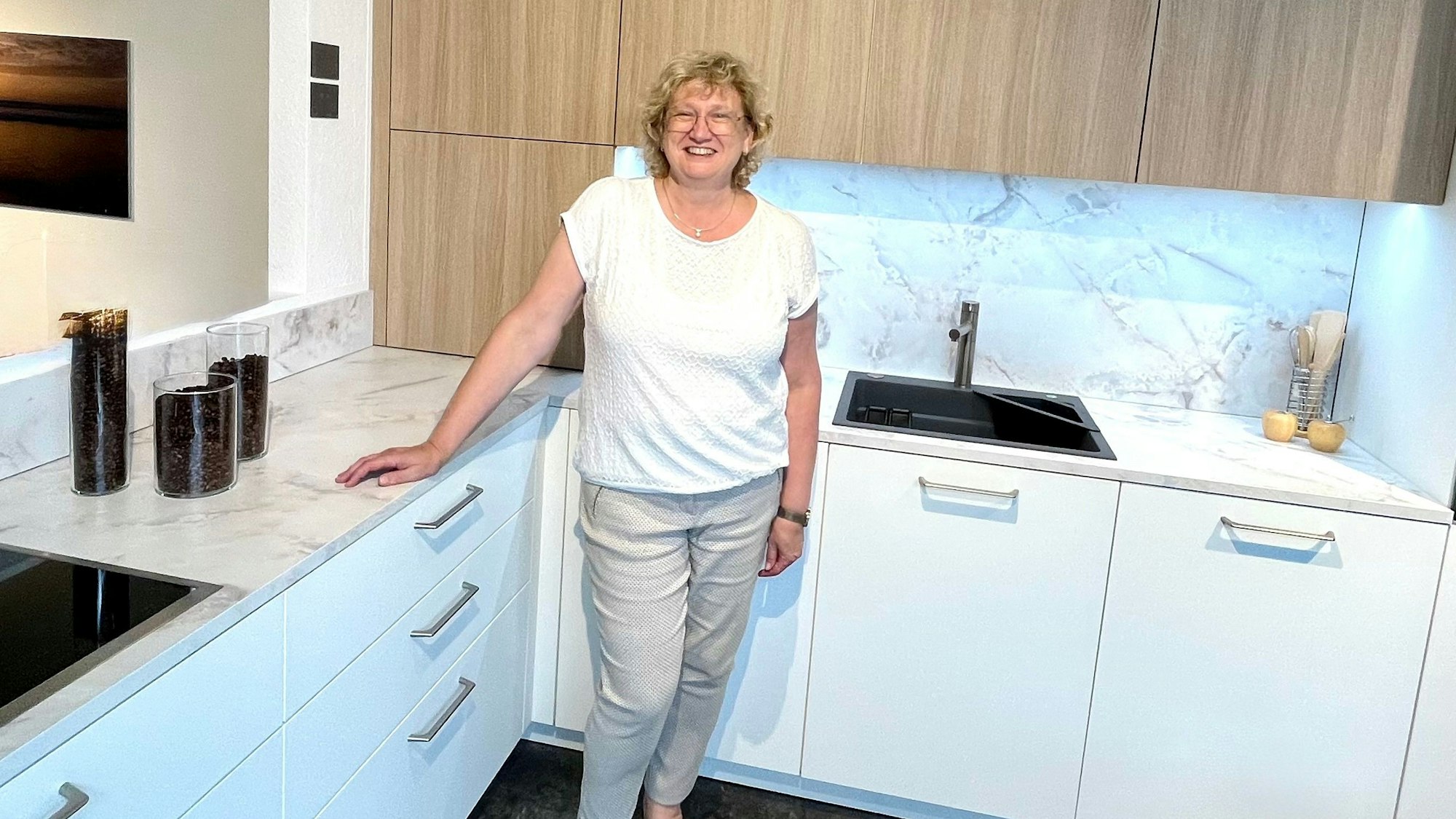 Eine Frau steht vor einer weißen Küche.