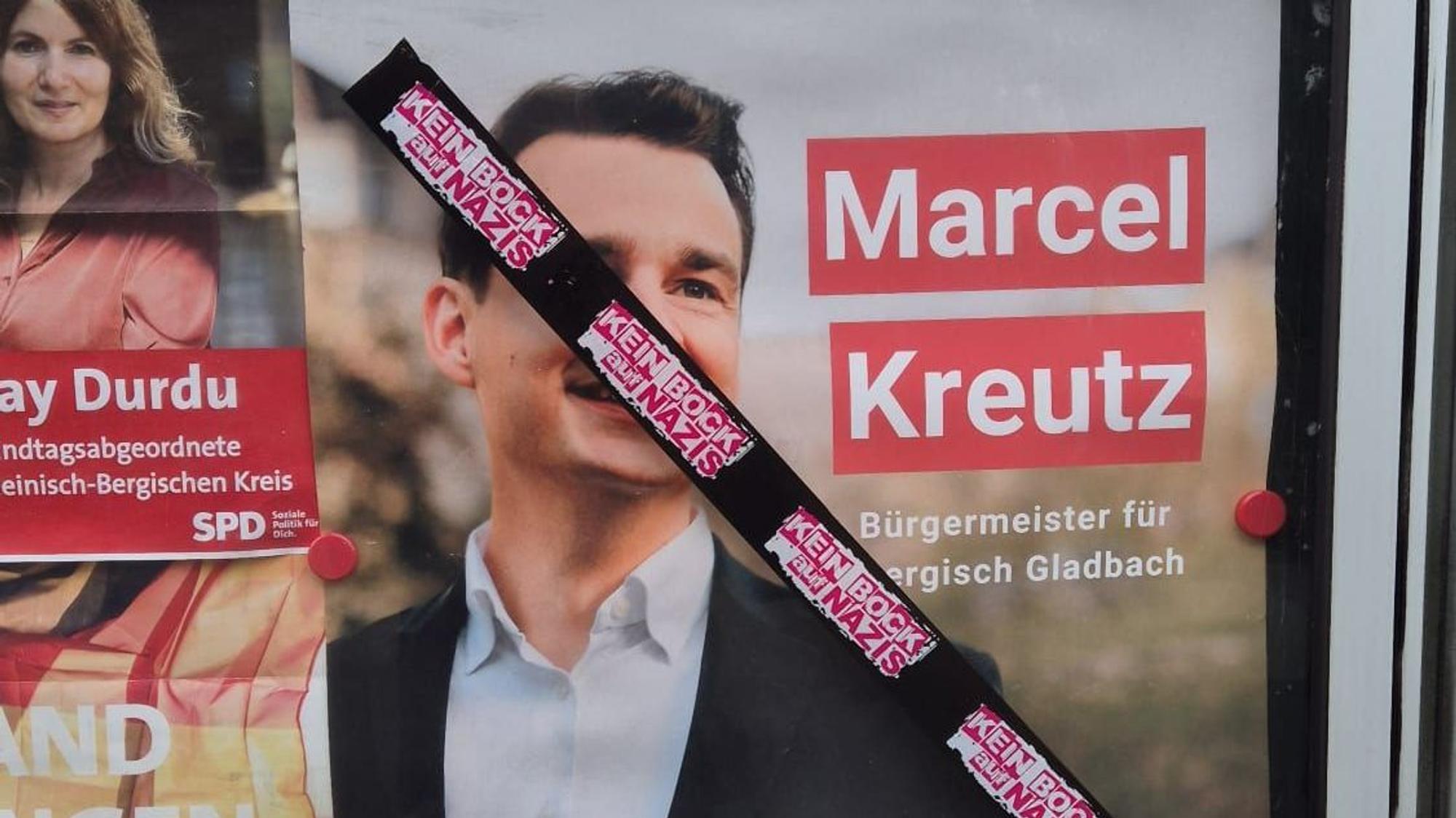Auf einem Schaukasten der SPD in Refrath mit einem Plakat von SPD/Grünen-Bürgermeisterkandidat Marcel Kreutz prangt eine Reihe von Aufklebern mit der Aufschrift „Kein Bock auf Nazis“.