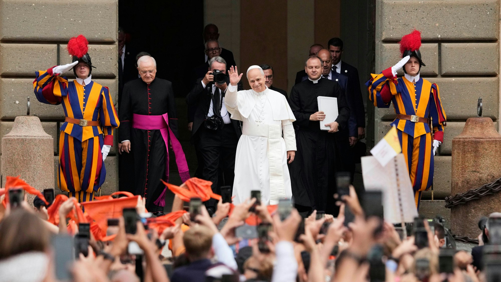 Papst Leo XIV. winkt nahe seiner Sommerresidenz Gläubigen zu. Ihn flankieren Schweizergardisten.