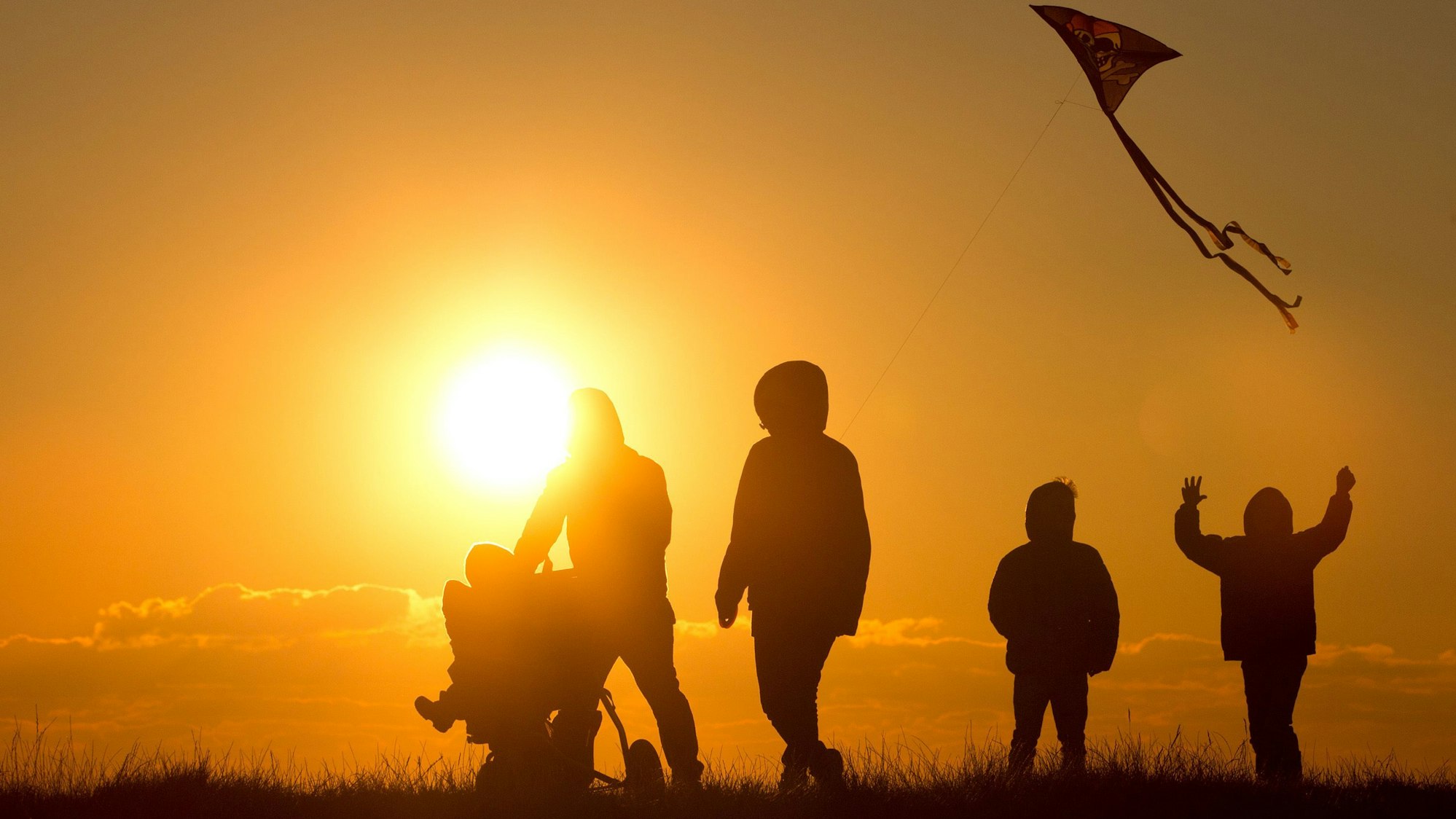 Eine Familie mit Kinderwagen und Drachen im Schlepptau