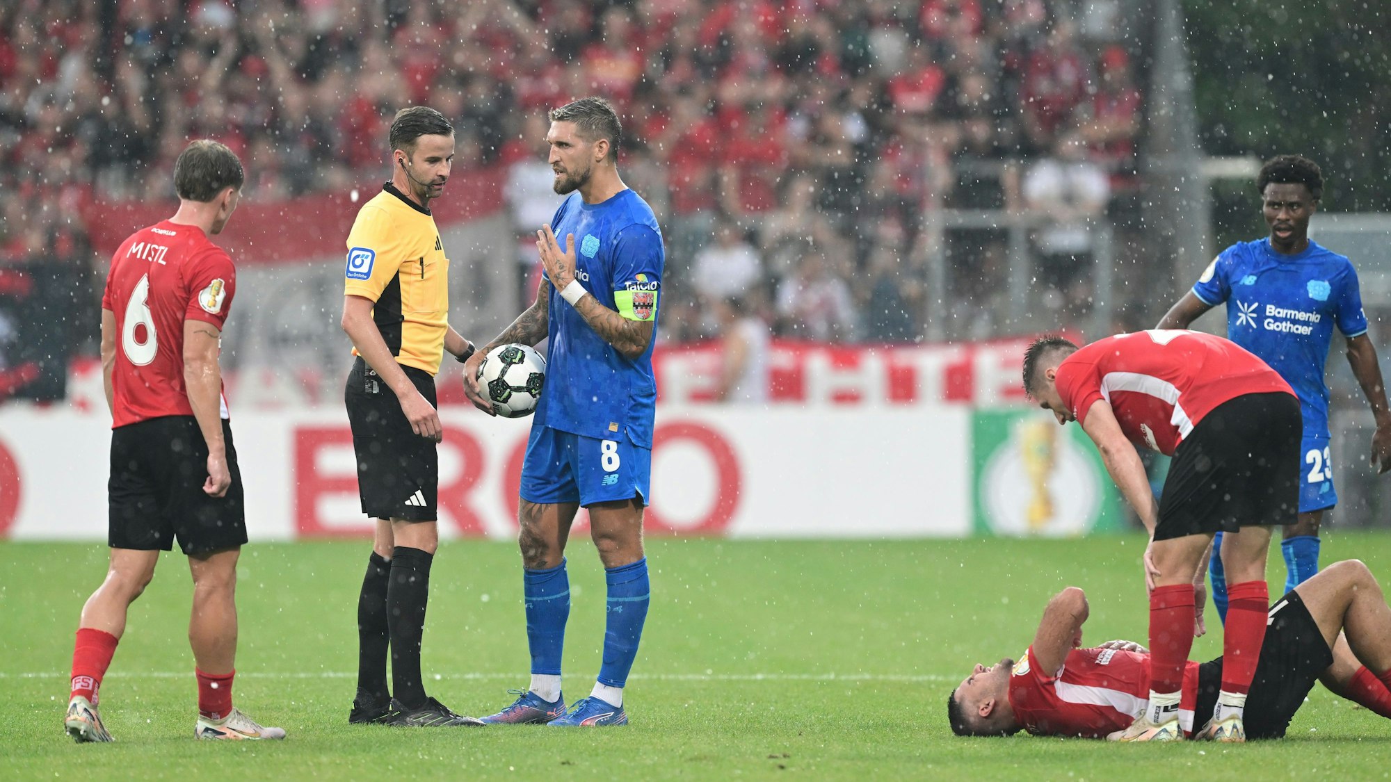 Robert Andrich (3.v.l, Bayer Leverkusen) spricht mit dem Schiedsrichter Michael Bacher (2.v.l).
