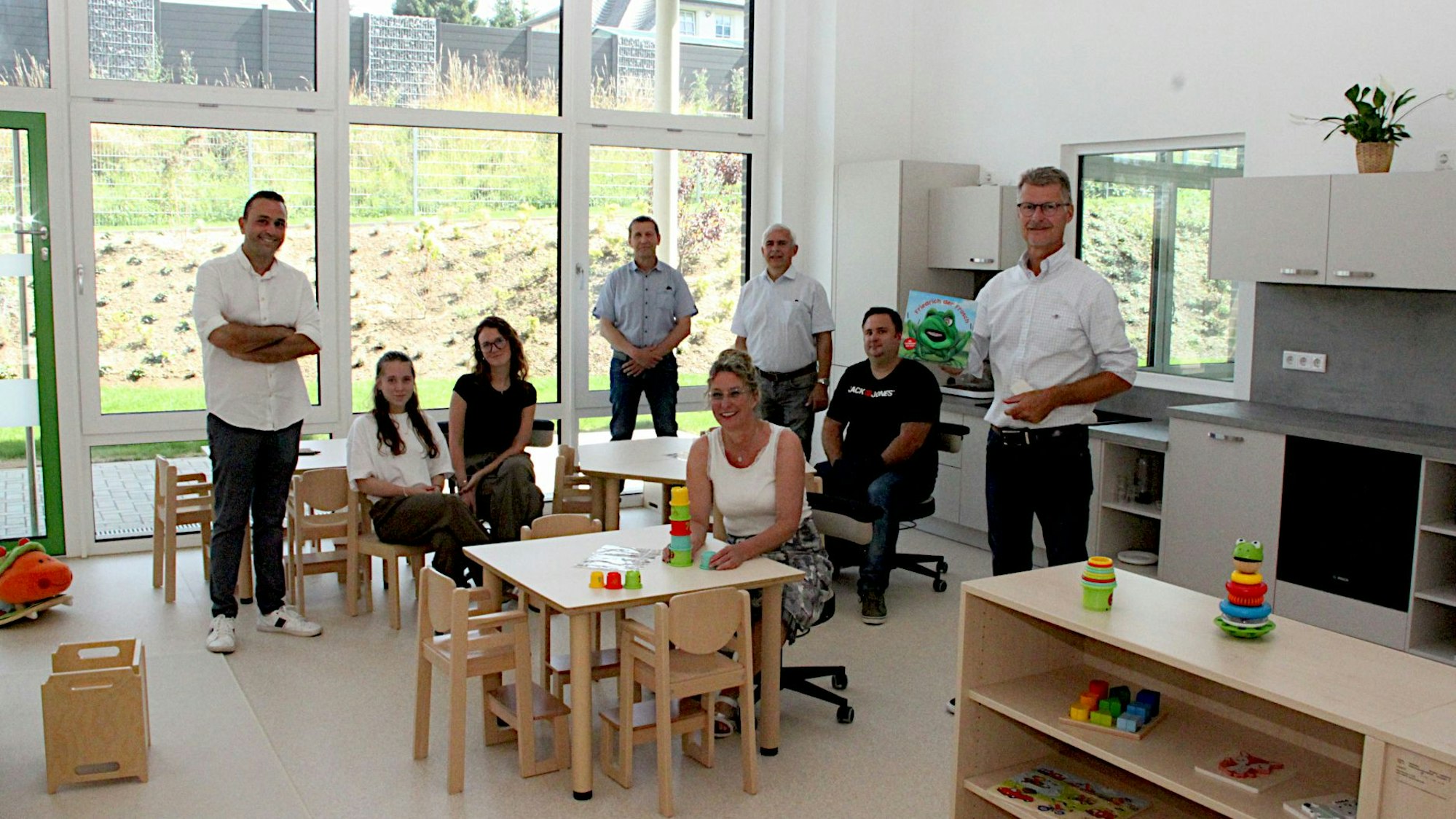 Eine Gruppe Männer und Frauen schaut sich die neuen Räume an, einige sitzen auf der Kinderstühlen.