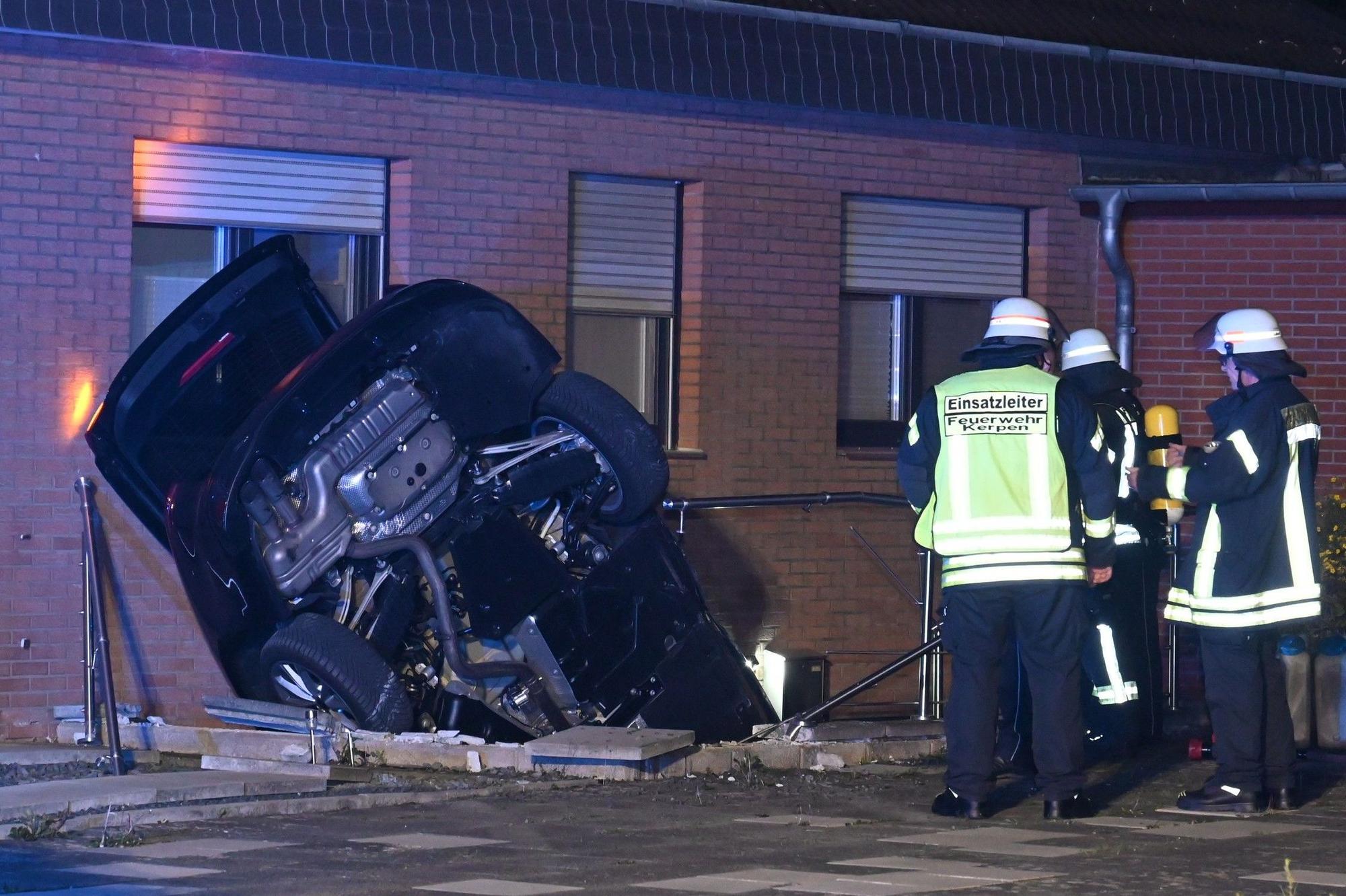 Das Bild zeigt ein Auto, das an einer Hauswand in einem Kellerabgang steckt.