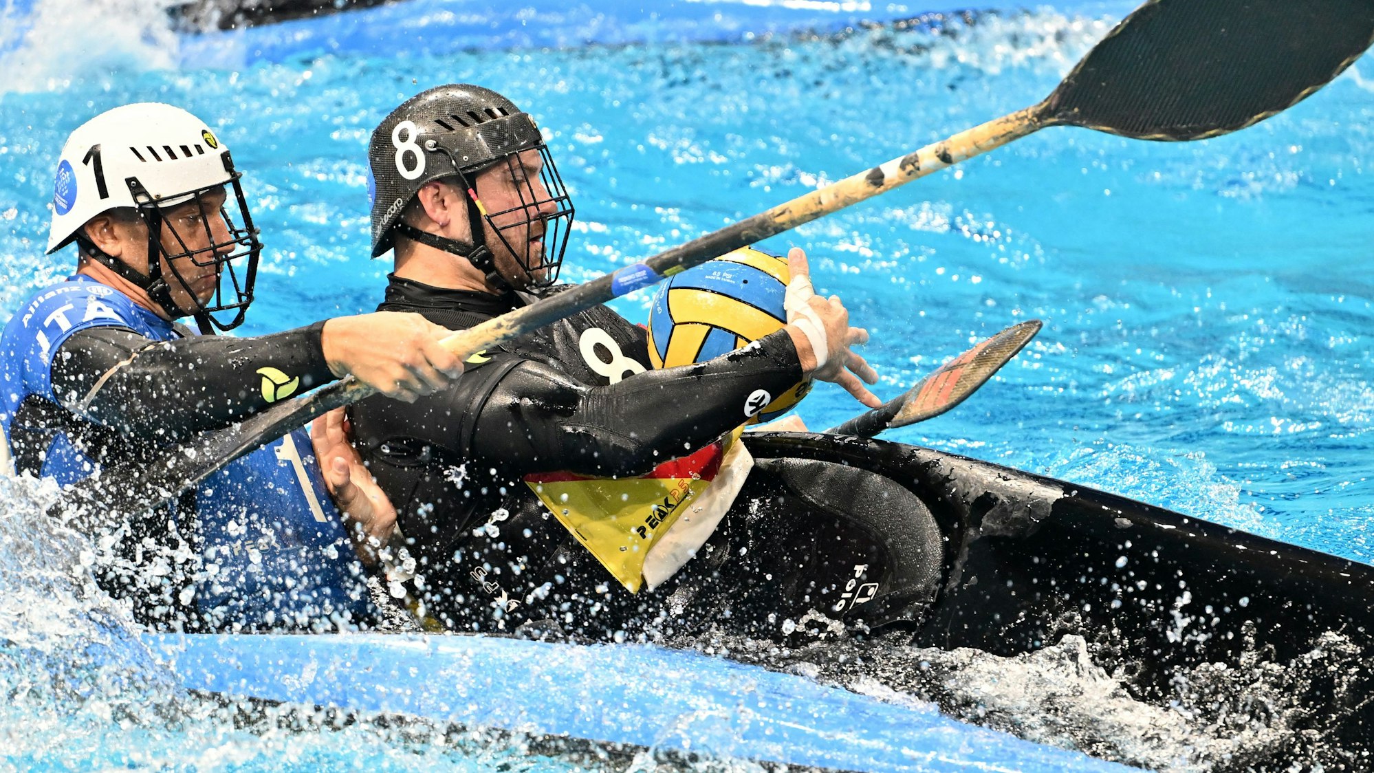 Das Foto zeigt zwei Männer in ihren Kanus, die sich im Kampf um den Ball befinden.
