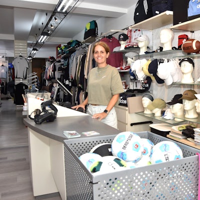 Eine Frau steht hinter der Kasse eines Sportgeschäfts.