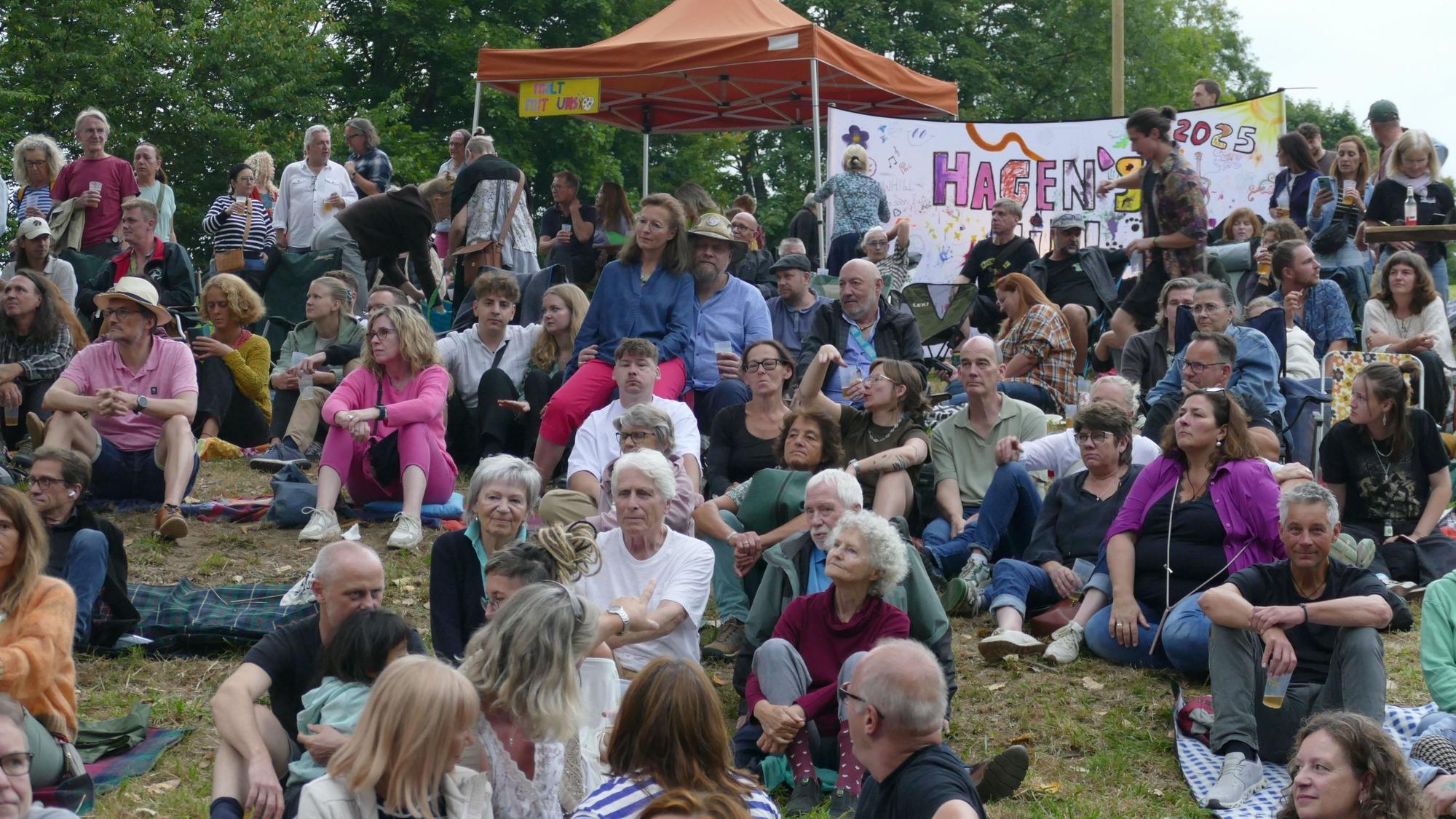 Menschen sitzen auf einer Wiese.
