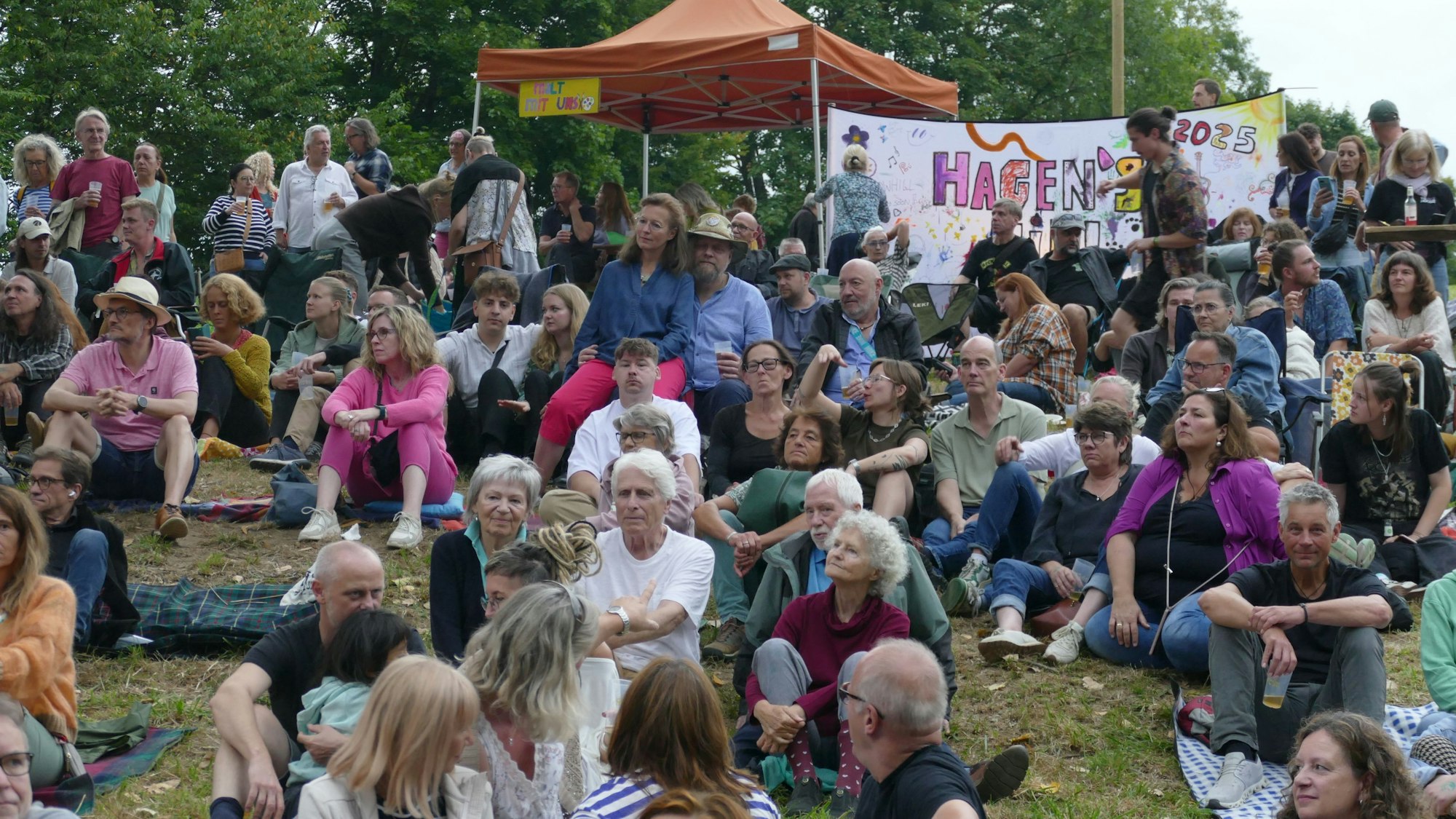 Menschen sitzen auf einer Wiese.