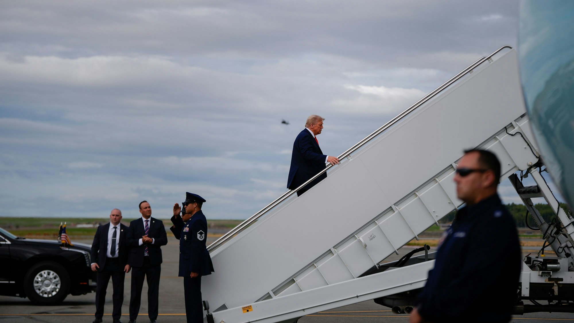 16.08.2025, USA, Joint Base Elmendorf-Richardson: US-Präsident Donald Trump (oben) besteigt die Air Force One auf der Joint Base Elmendorf-Richardson nach einem Treffen mit dem russischen Präsidenten Putin. Foto: Julia Demaree Nikhinson/AP/dpa +++ dpa-Bildfunk +++