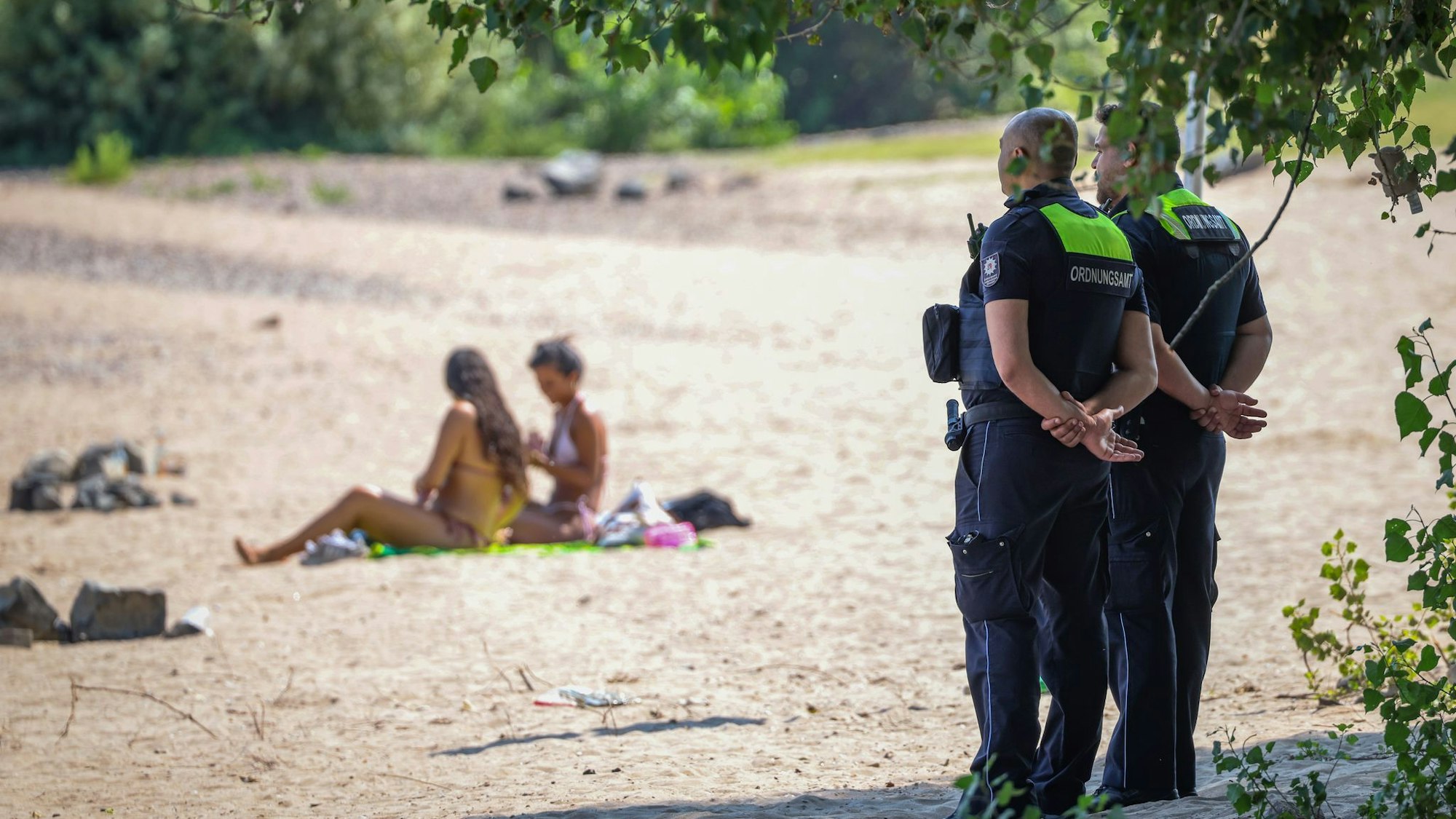 Mitarbeiter vom Ordnungsamt der Stadt Düsseldorf sind am sogenannten Paradiesstrand im Einsatz. Sie überwachen das Badeverbot im Rhein.
