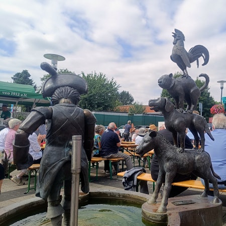 Das Foto zeigt voll besetzte Bänke hinter dem Brunnen beim Brunnenfest.