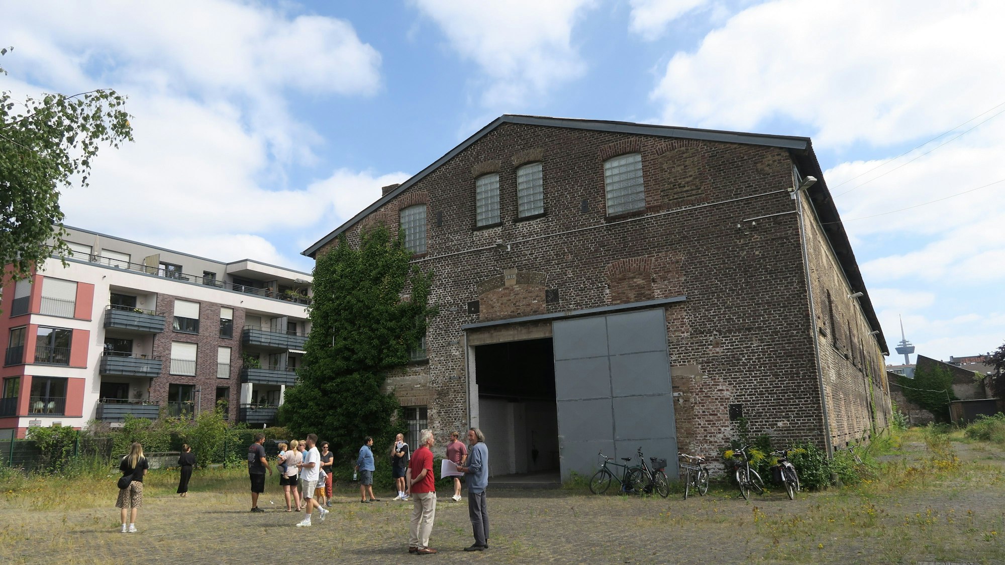Eine Gruppe Menschen steht vor reiner riesigen Backstein-Halle.