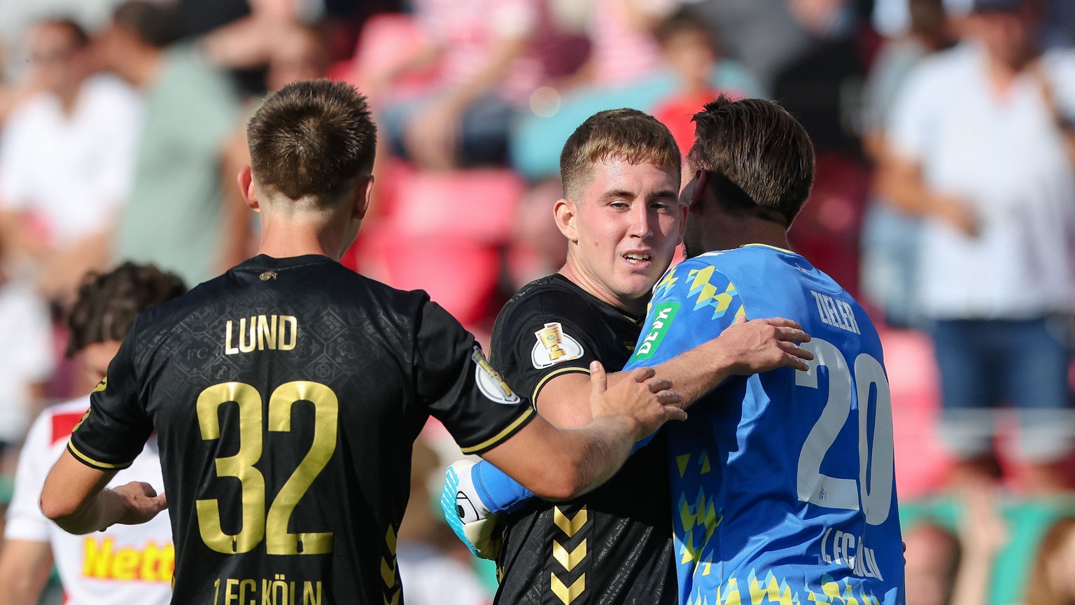Isak Johannesson vom 1.FC Köln (M) wird Torwart und Kapitän Ron-Robert Zieler (r) und Kristoffer Lund vom 1. FC Köln nach dem Siegtreffer zum 2:1-Sieg bejubelt.