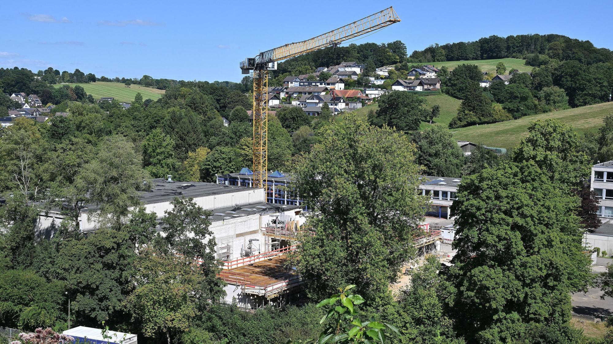 Ein großer Baukran steht auf der Baustelle einer Schule.