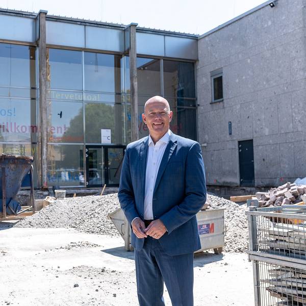 Das Foto zeigt Landrat Frank Rock auf der Baustelle vor der Glasfassade am Eingang des Berufskollegs.