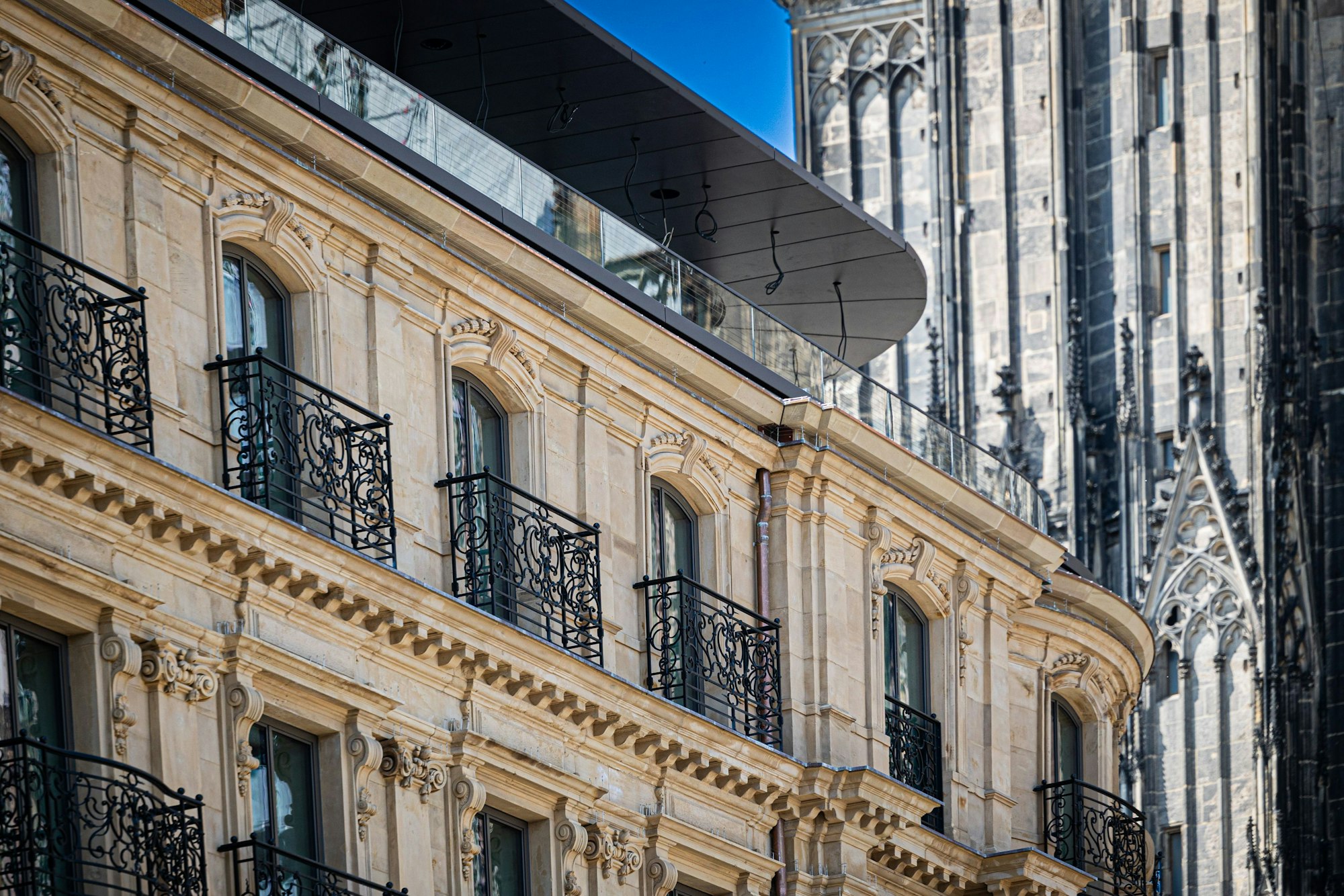 Im Dreiklang: Die historische Fassade des Hotels, das moderne Glasgeländer der Dachterrasse und der Dom im Hintergrund.