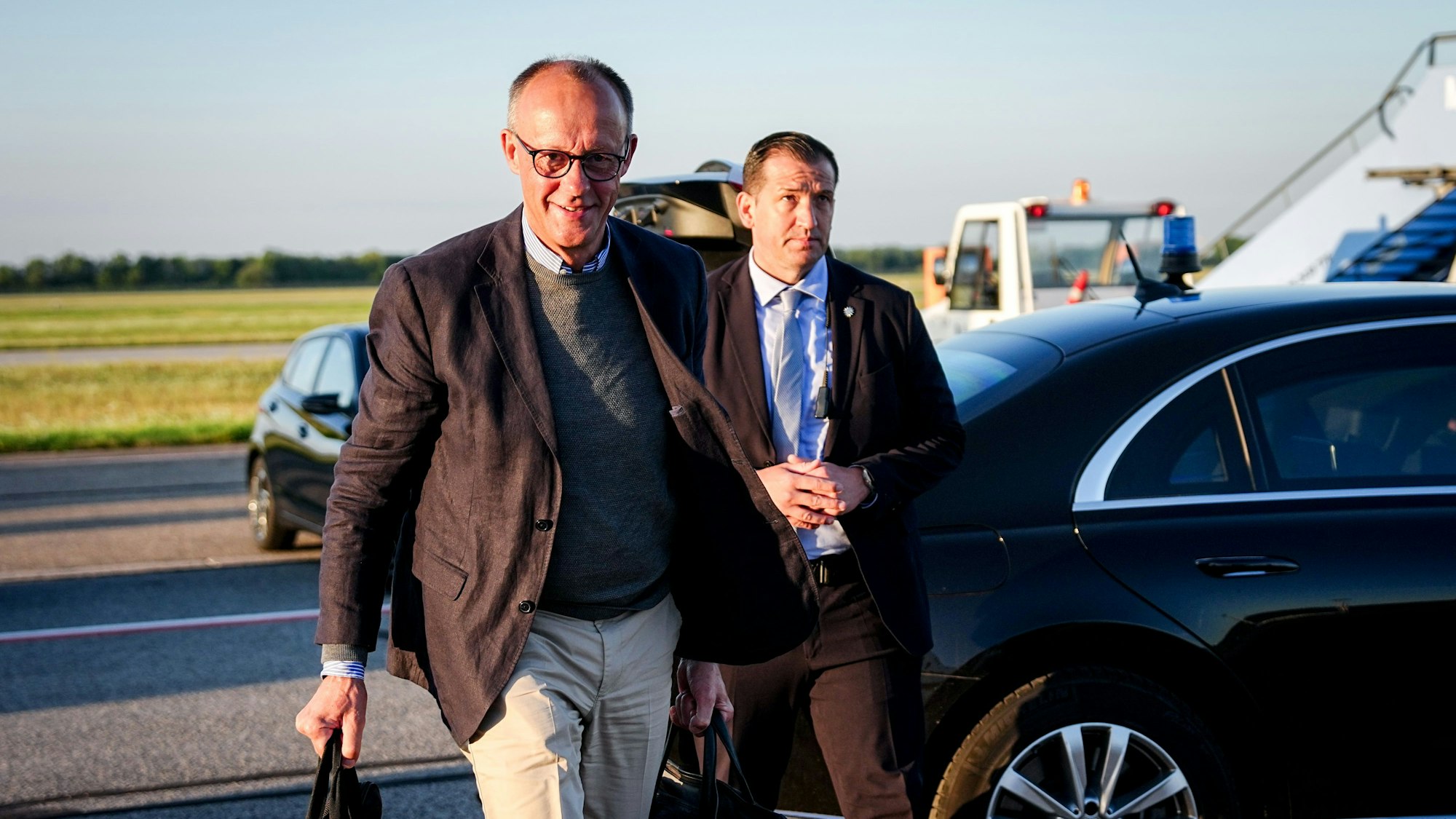 Bundeskanzler Friedrich Merz (CDU,l) geht auf dem Franz-Josef-Strauß-Flughafen zum Airbus A319 der Luftwaffe für den Flug nach Washington.