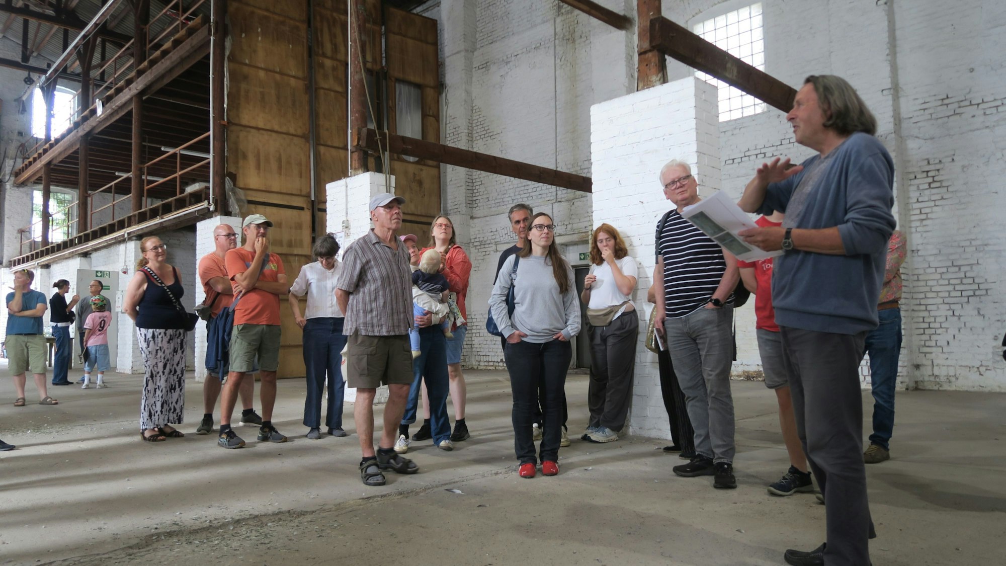 Menschen stehen in einer großen Halle, einer spricht.