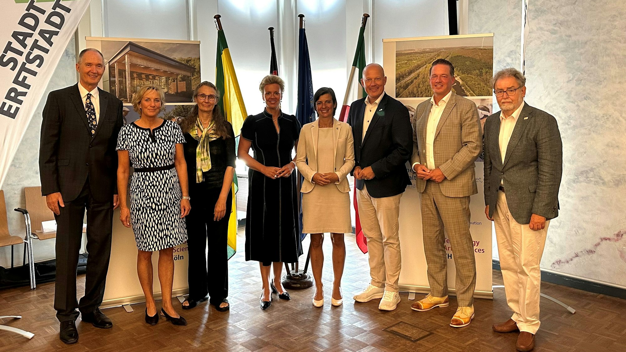 Frauen und Männer stehe nebeneinander und lächeln.