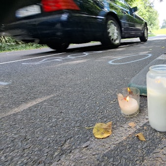 Zwischen Warnbaken stehen Kerzen auf der Dürschtalstraße, auf der sich am Samstag (16.8.) ein tödlicher Unfall ereignet hat, bei dem vier Teenager im Alter von 14 bis 19 Jahren ums Leben kamen.