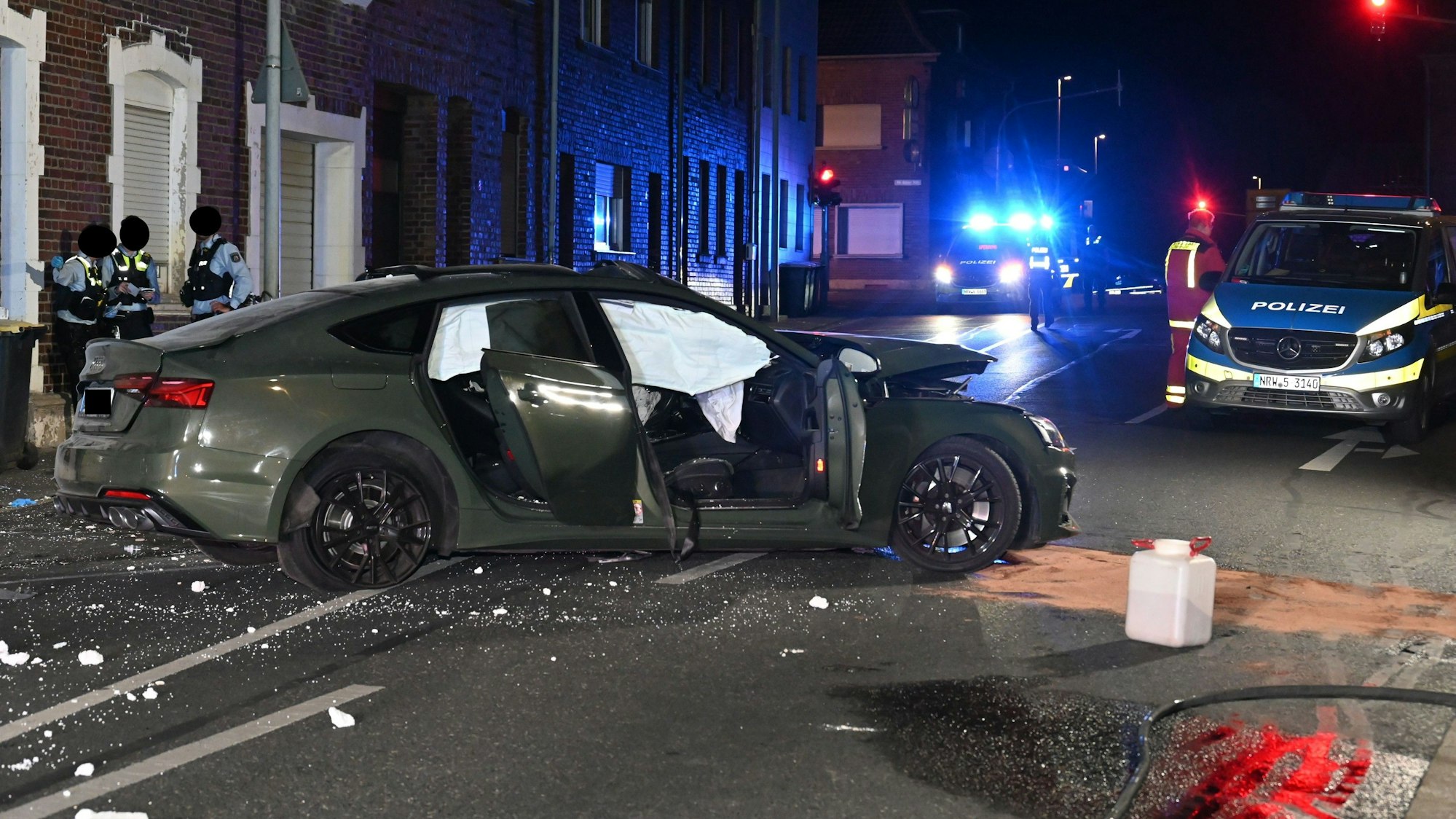 Das Fahrzeug nach dem Unfall. Im Hintergrund Einsatzkräfte der Polizei und ein Einsatzfahrzeug.