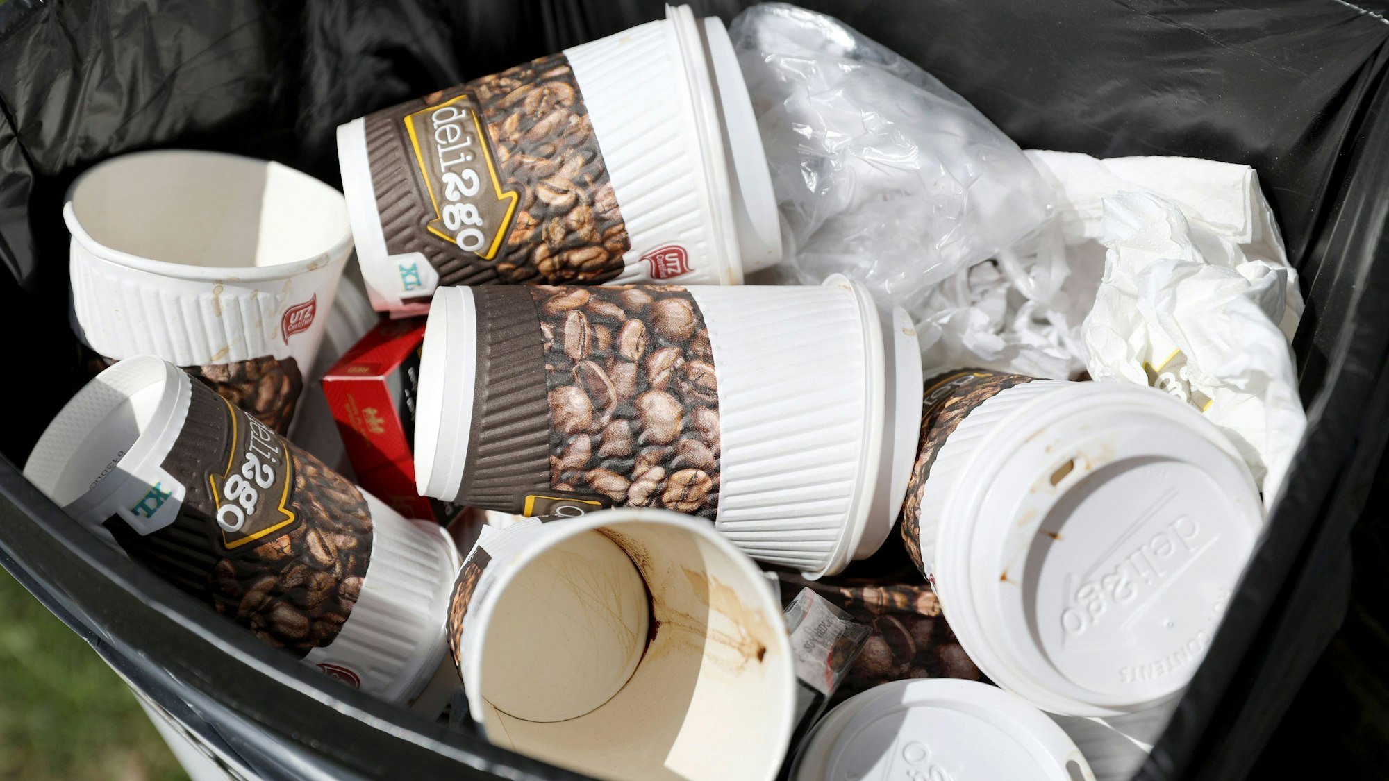 Benutzte Einweg-Kaffeebecher liegen in einem Papierkorb