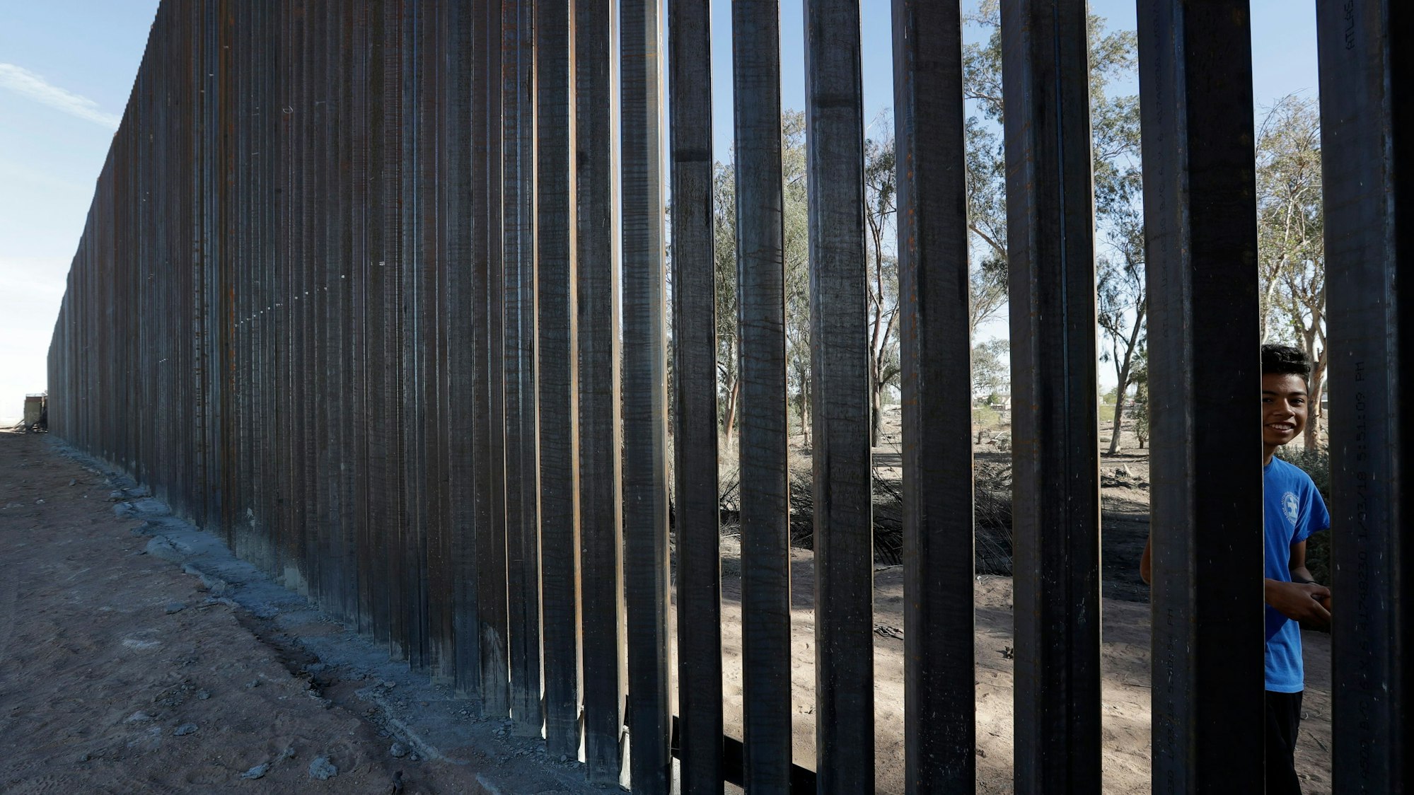 Ein Junge blickt durch die Stäbe eines neuen Grenzzaunes entlang der US-amerikanischen Grenze zwischen Calexico (USA, links) und Mexicali (Mexiko, rechts).