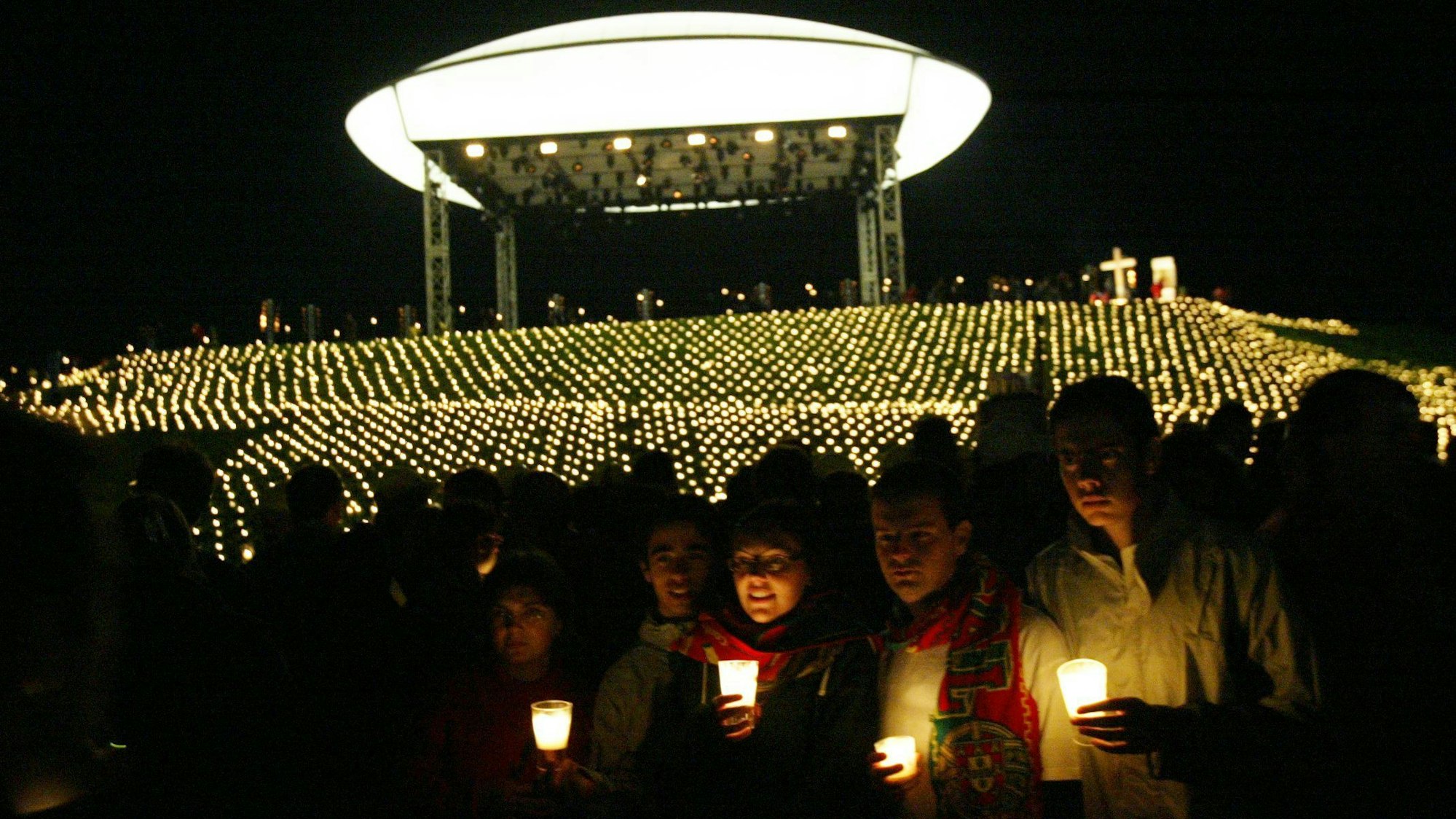 Pilger halten vor dem Papsthügel auf dem Marienfeld bei Kerpen Kerzen in der Hand.
