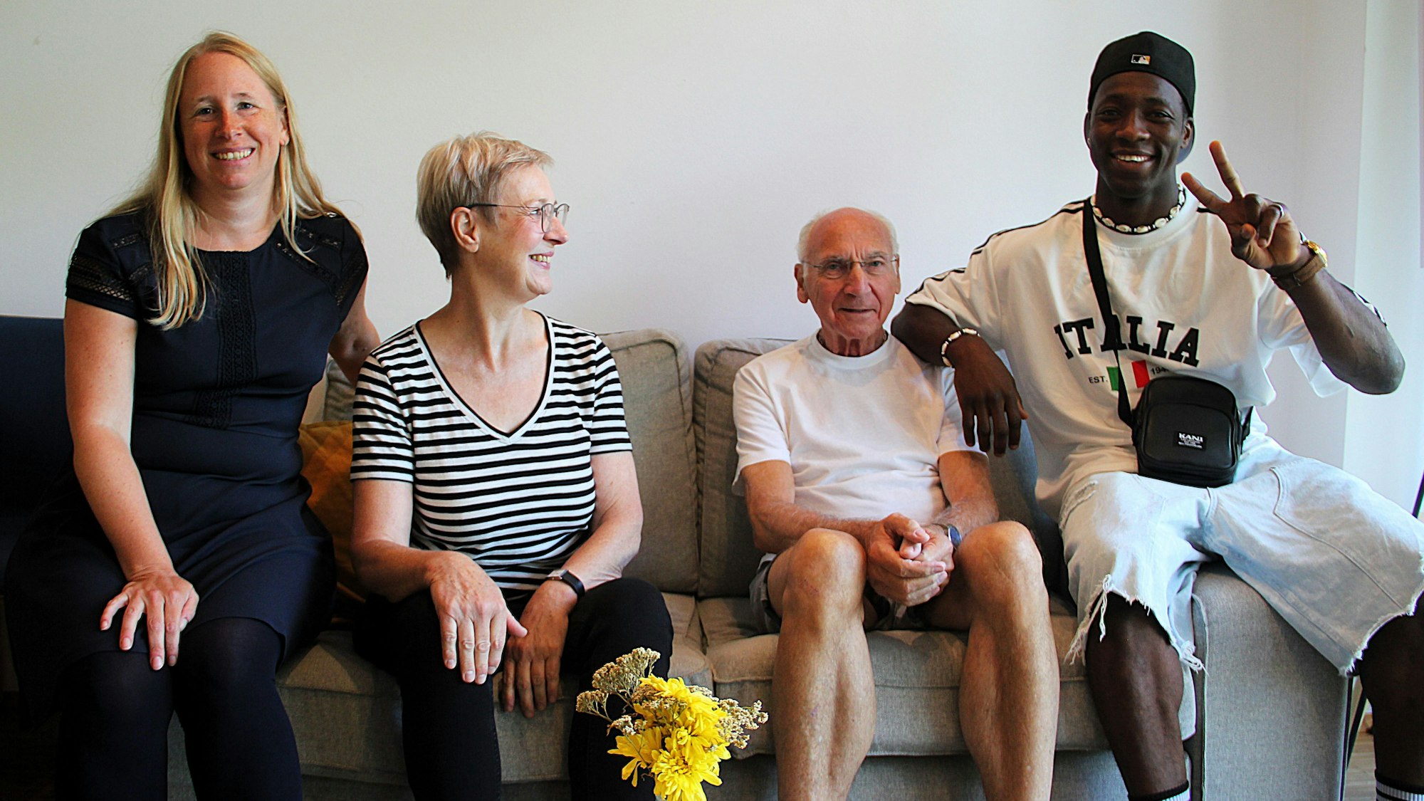 Vier Menschen sitzen nebeneinander auf einem Sofa.