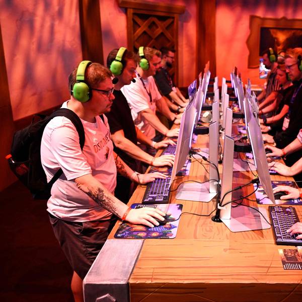 Am ersten Tag der Gamescom 2025: Besucher testen das Videospiel „World of Warcraft Midnight“. Sie sitzen jeweils vor einem Computer und tragen neongrüne Headsets.