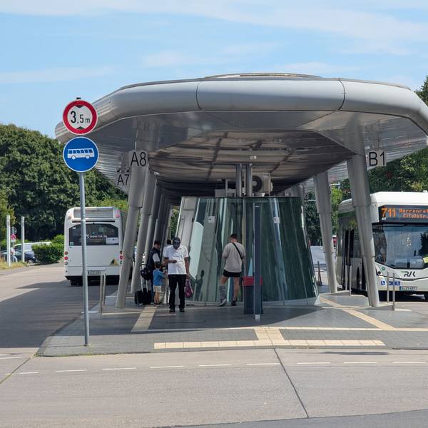 Das Foto zeigt zwei Busse und wartende Fahrgäste am Busbahnhof in Hürth-Mitte.