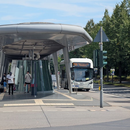 Das Foto zeigt zwei Busse und wartende Fahrgäste am Busbahnhof in Hürth-Mitte.