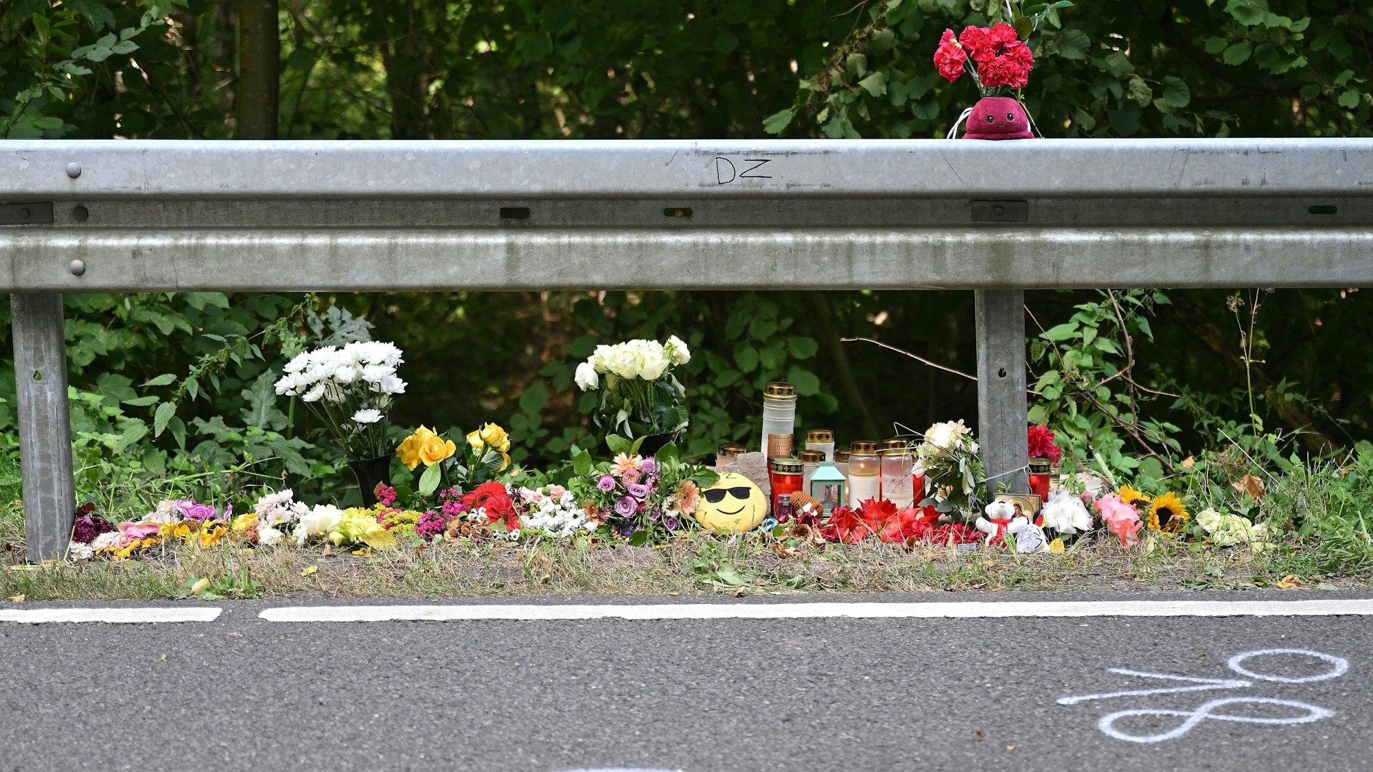 Auf beiden Seiten der Unfallstelle haben Menschen Blumen, Kerze und Kuscheltiere abgelegt.