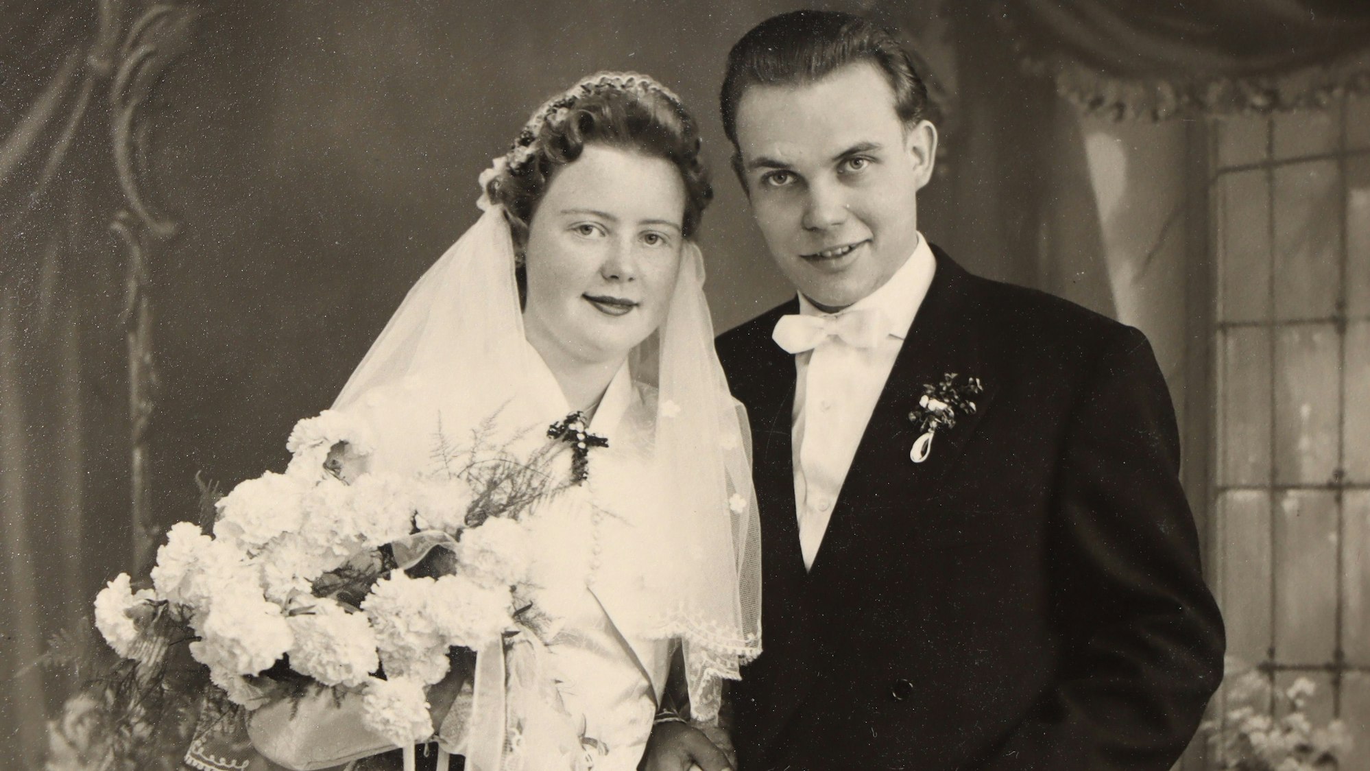 Zu sehen ist ein Brautpaar an seinem Hochzeitstag in schwarz-weiß.