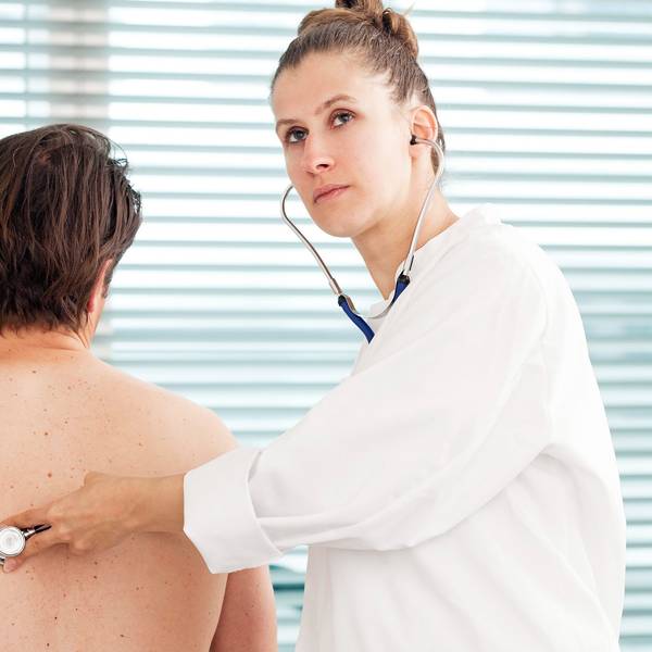 Eine Ärztin hört einen Patienten ab.