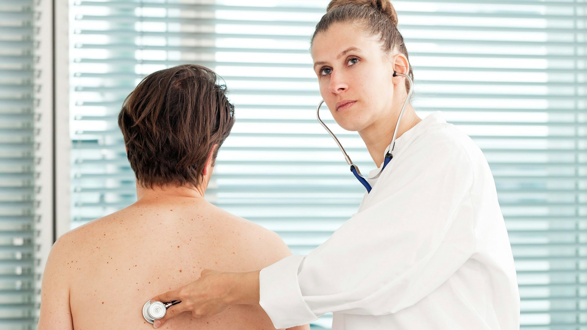 Eine Ärztin hört einen Patienten ab.