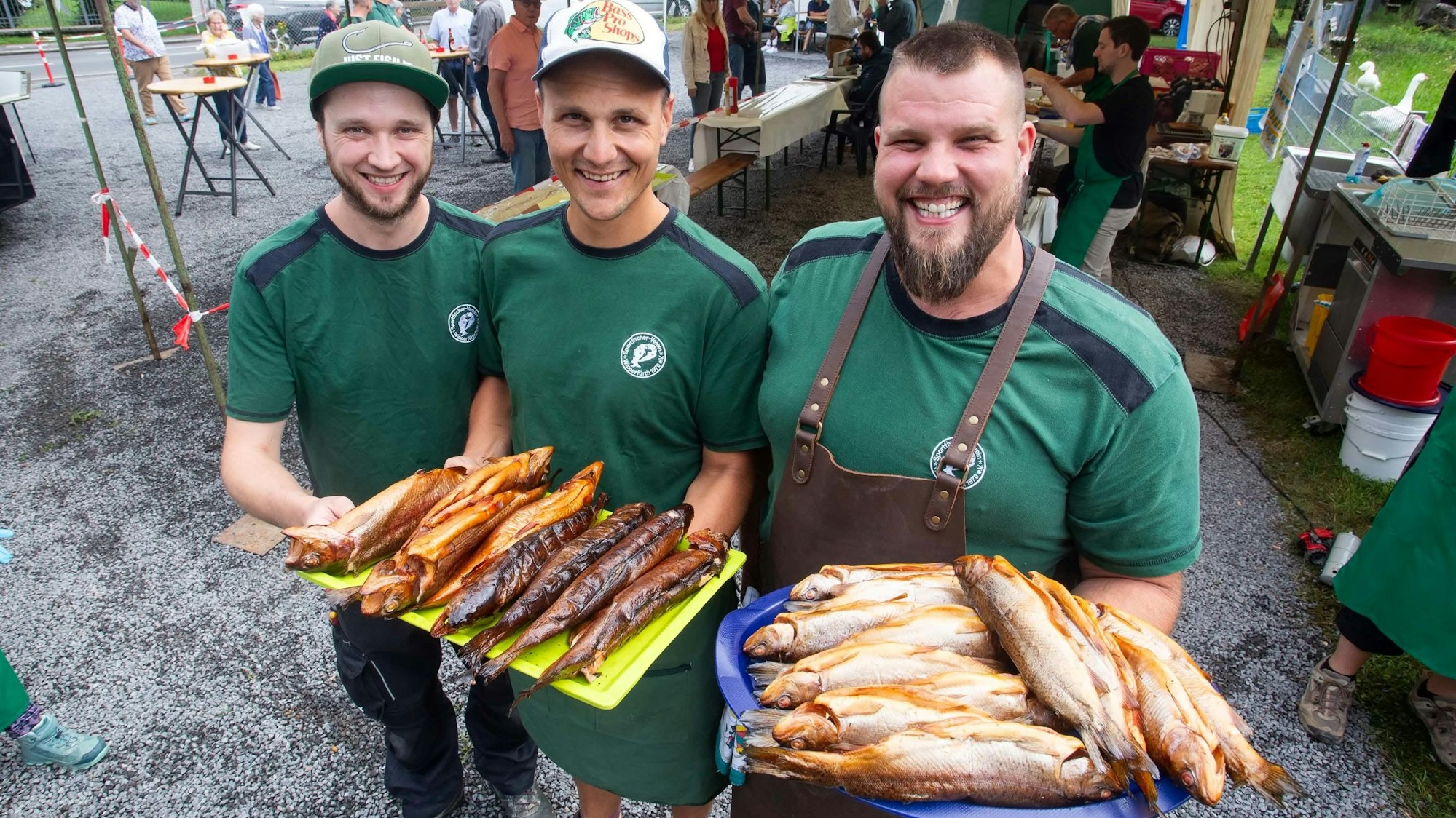 Drei junge Männer präsentieren geräucherten Fisch.
