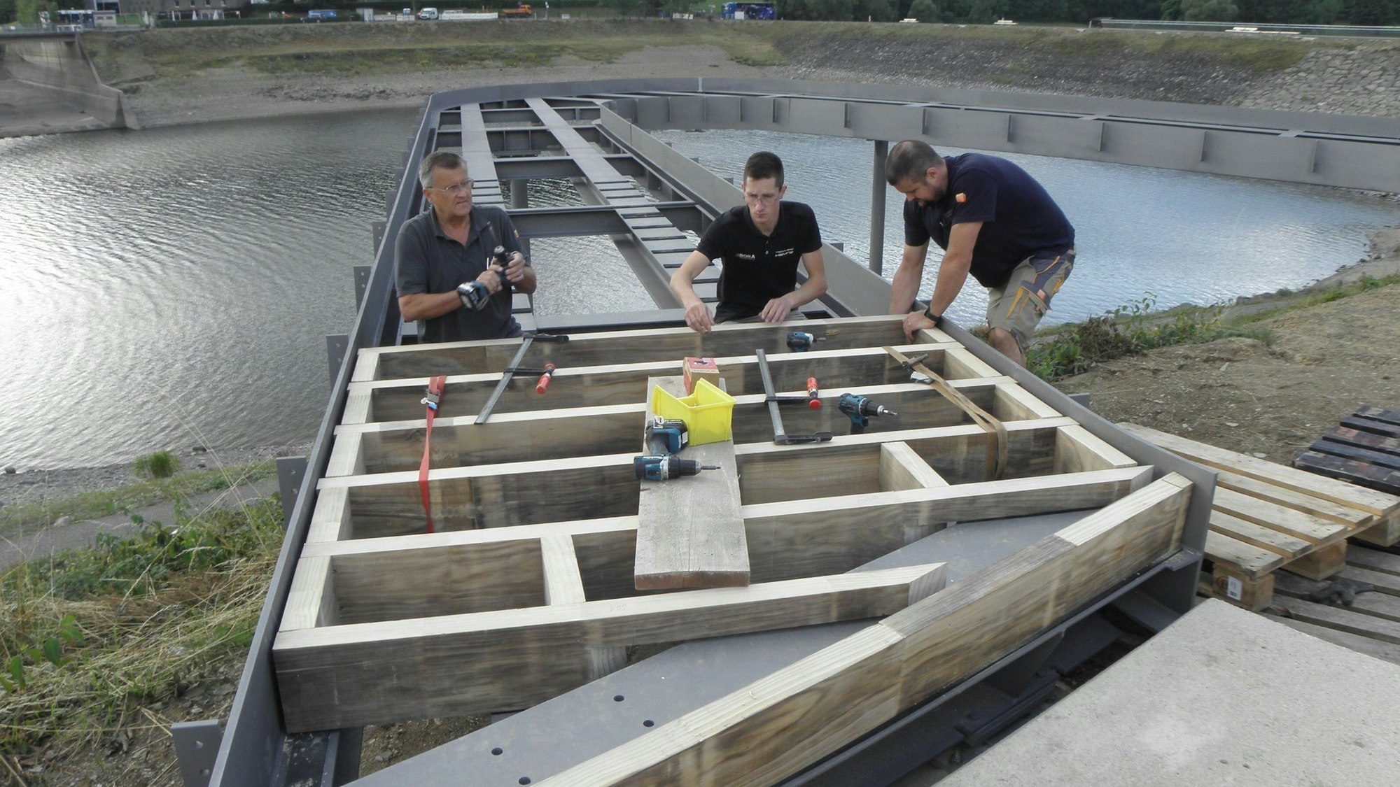 Drei Handwerker arbeiten an einem Holzgestell, das zu einem der Balkone entwickelt werden soll.